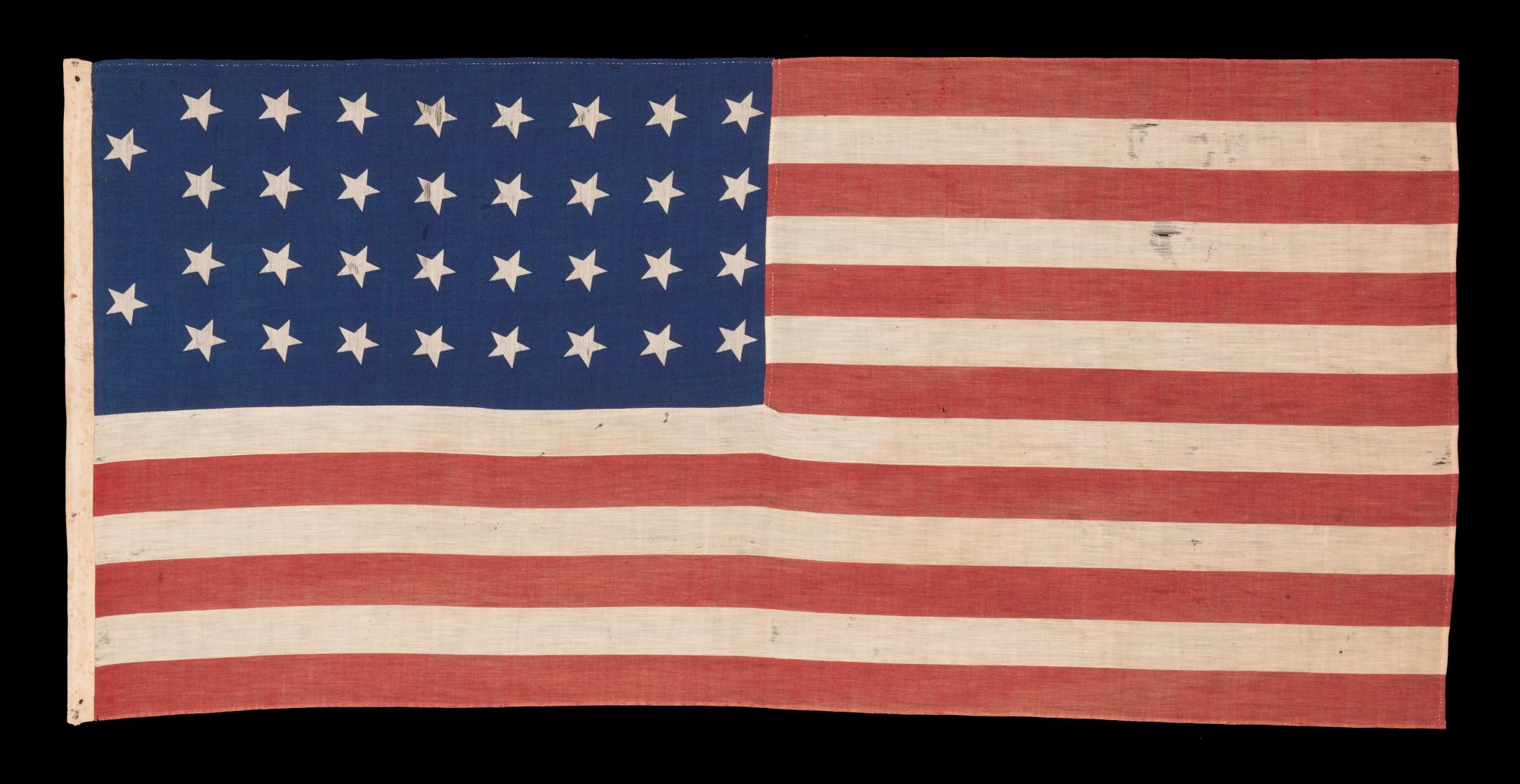 34 STARS IN 4 ROWS WITH 2 STARS OFFSET AT THE HOIST END, ON AN ANTIQUE AMERICAN FLAG LIKELY PRODUCED FOR MILITARY FUNCTION, AS UNION ARMY CAMP COLORS;  ONE OF JUST A TINY HANDFUL THAT I HAVE ENCOUNTERED IN THIS EXACT STYLE, REFLECTS KANSAS