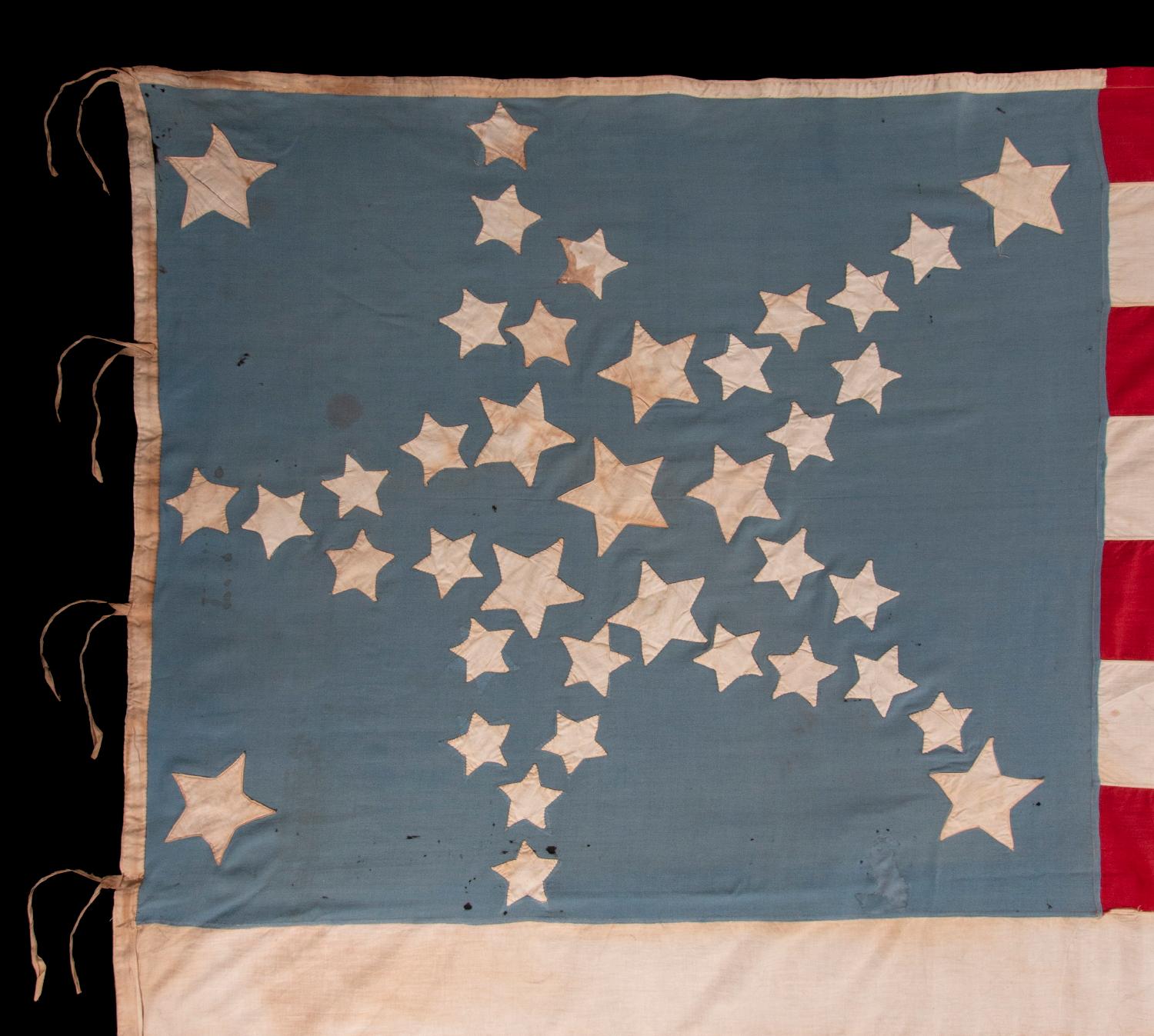 34 STERNE IN EINER SKURRILEN WIEDERGABE DES GROSSEN STERNENMUSTERS AUF EINER FLAGGE AUS DER BÜRGERKRIEGSZEIT MIT KORNBLUMENBLAUEM KANTON, 1876 AUF 39 STERNE AKTUALISIERT

Amerikanische Nationalflagge mit 34 Sternen und zusätzlichen Sternen und einem