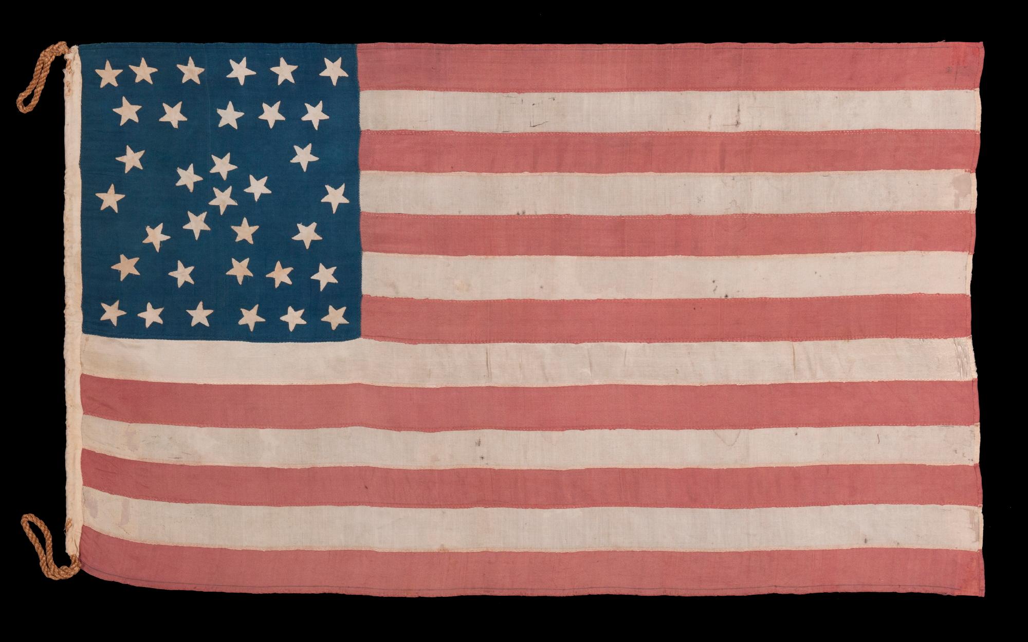 EXTRAORDINARY 34 STAR ANTIQUE AMERICAN FLAG WITH AN ACCORDION OR HOURGLASS MEDALLION CONFIGURATION THAT SURROUNDS A PENTAGON OF STARS IN THE CENTER; MADE OF FINE SILK AND ENTIRELY HAND-SEWN; MADE DURING THE OPENING YEARS OF THE CIVIL WAR (1861-63),