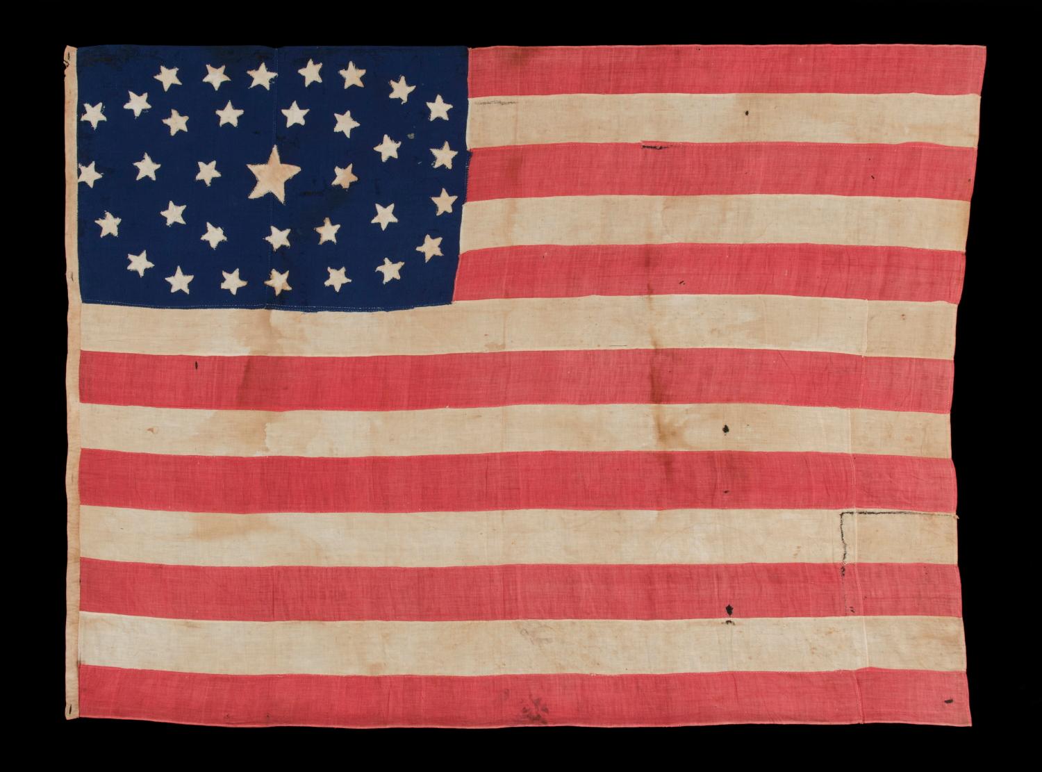 34 STARS IN AN OUTSTANDING OVAL MEDALLION CONFIGURATION, ON A NARROW CANTON THAT RESTS ON THE 6TH STRIPE, ON A HOMEMADE, ANTIQUE AMERICAN FLAG OF THE CIVIL WAR PERIOD, ENTIRELY HAND-SEWN, 1861-1863, KANSAS STATEHOOD:

34 star American national flag