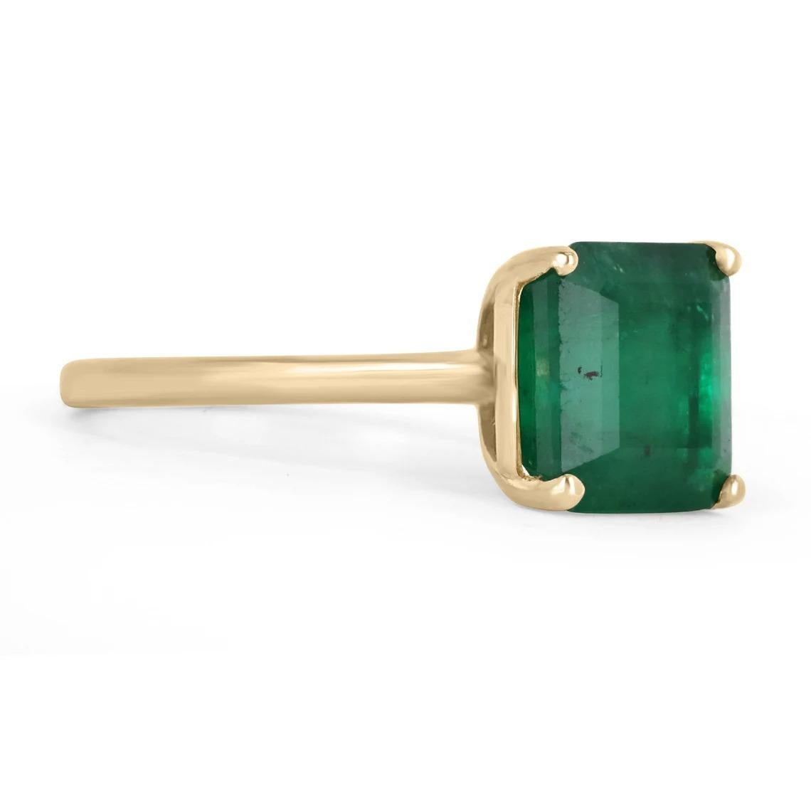 Displayed is a classic Brazilian emerald solitaire emerald-cut engagement ring/right-hand ring in 14K yellow gold. This gorgeous solitaire ring carries a full 3.40-carat emerald in an offset four-prong setting. Fully faceted, this gemstone showcases