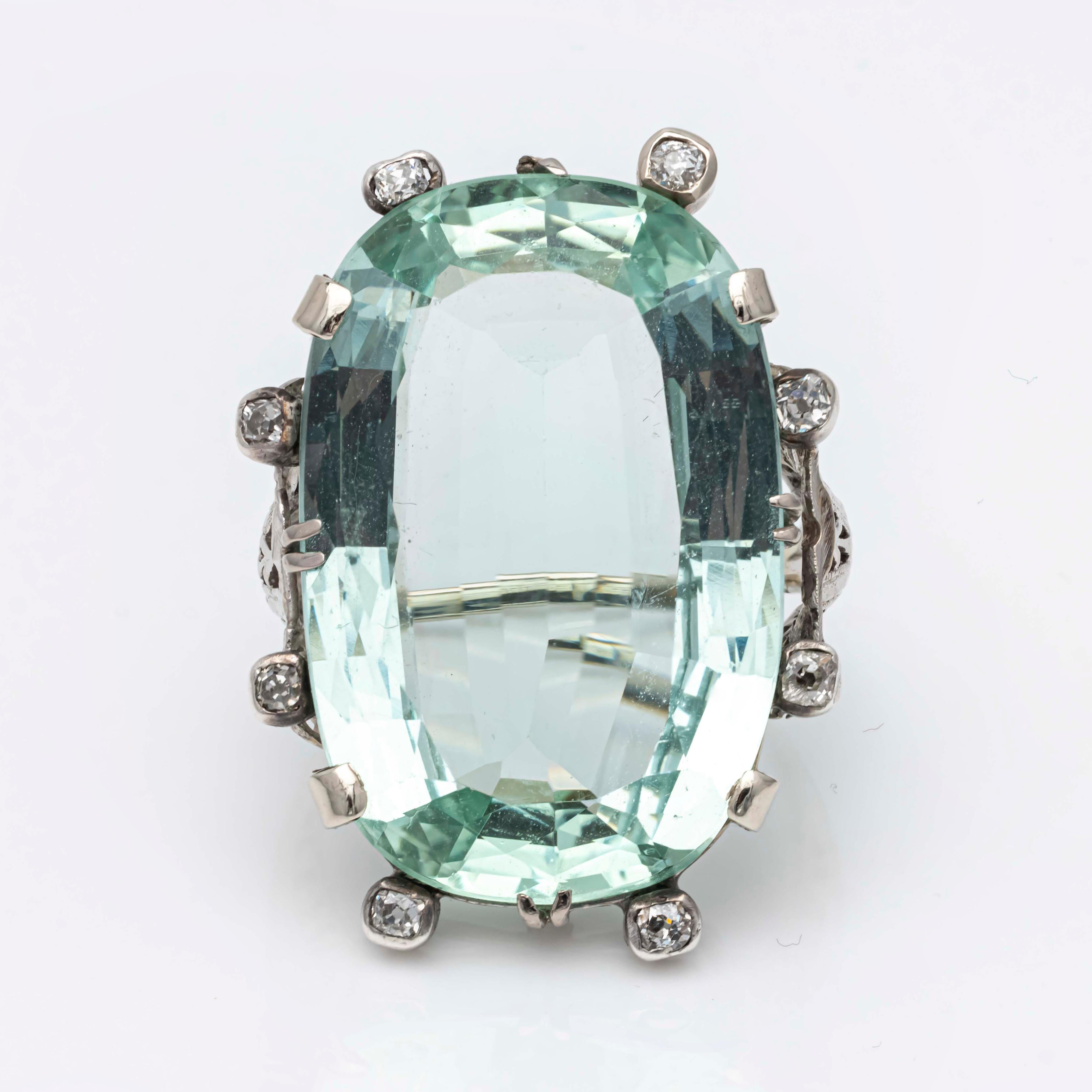 A beautiful cocktail ring that features a large, natural green aquamarine stone weighing 34.18 carats set in an intricate antique ring design. Accented by 8 old mine cut diamonds weighing 0.42 carats total. Finely made in 18K white gold. Size 7.5