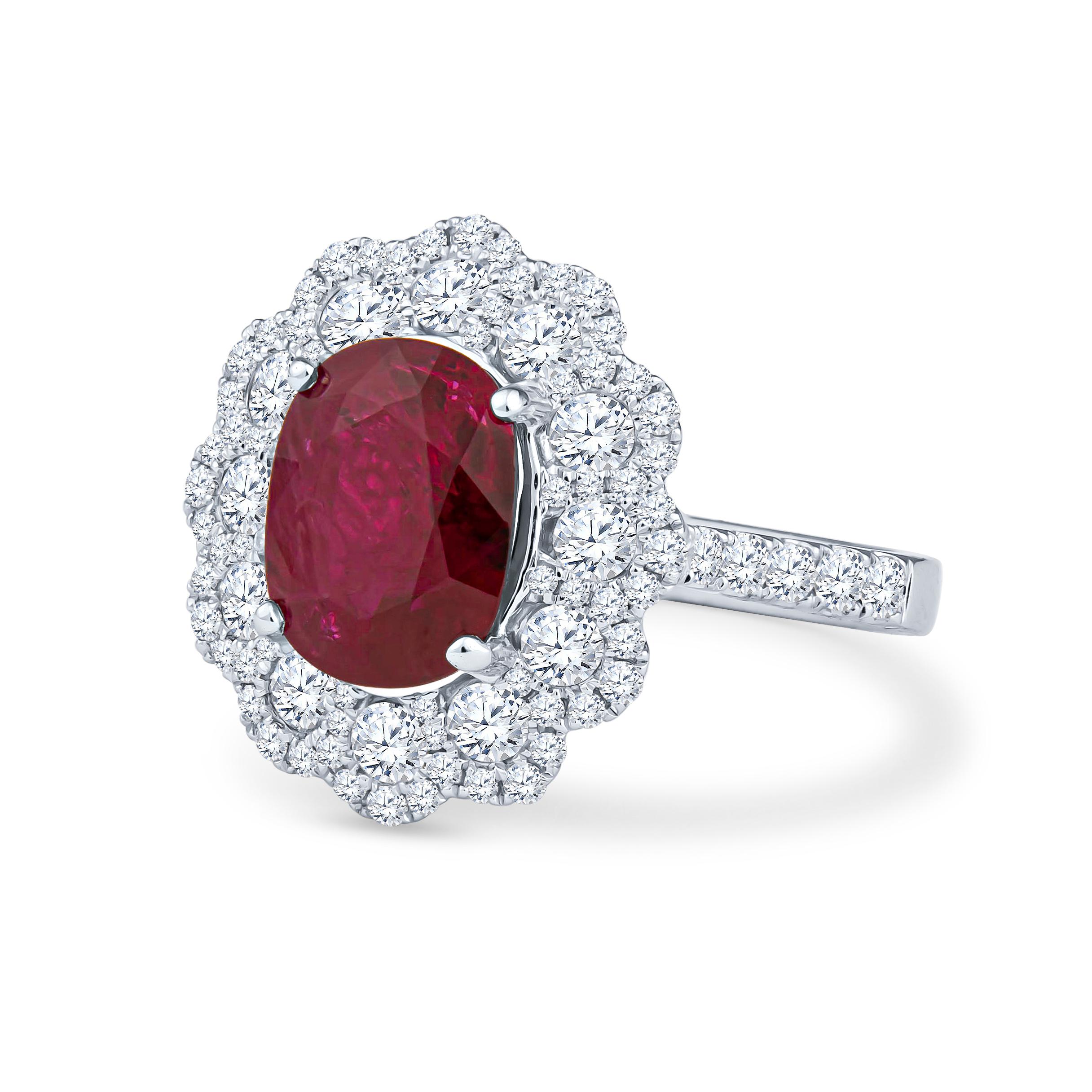 This stunning, pure red 3.41ct ruby is a natural gem from Thailand, cut in an oval shape. It is a rich, nicely saturated color that is not too dark or too light. It is set in an 18kt white gold decorative oval halo cathedral ring. Surrounding the