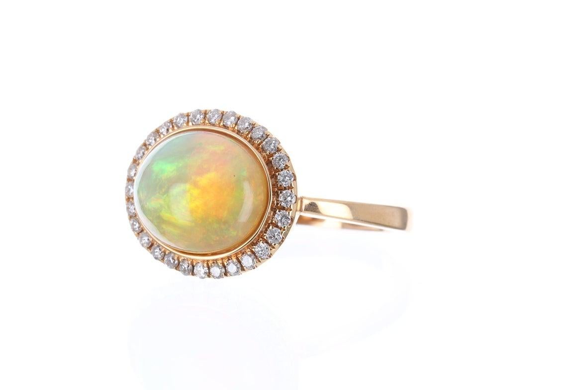 A one of kind, couture-inspired sunset 3.11 carat opal and diamond halo ring. Make it your engagement ring or right-hand ring, it is the perfect statement piece! The focal point in this beautiful ring is a natural, solid opal filled with
