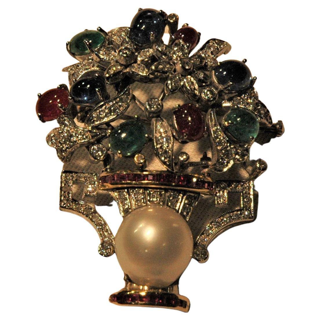 This is a wonderful flower brooch, handmade in Italy. It is realized in white gold with diamonds, three blu cabochon sapphires, three cabochon emeralds, three cabochon rubies, some small carré and baguette rubies and a central white pearl. It