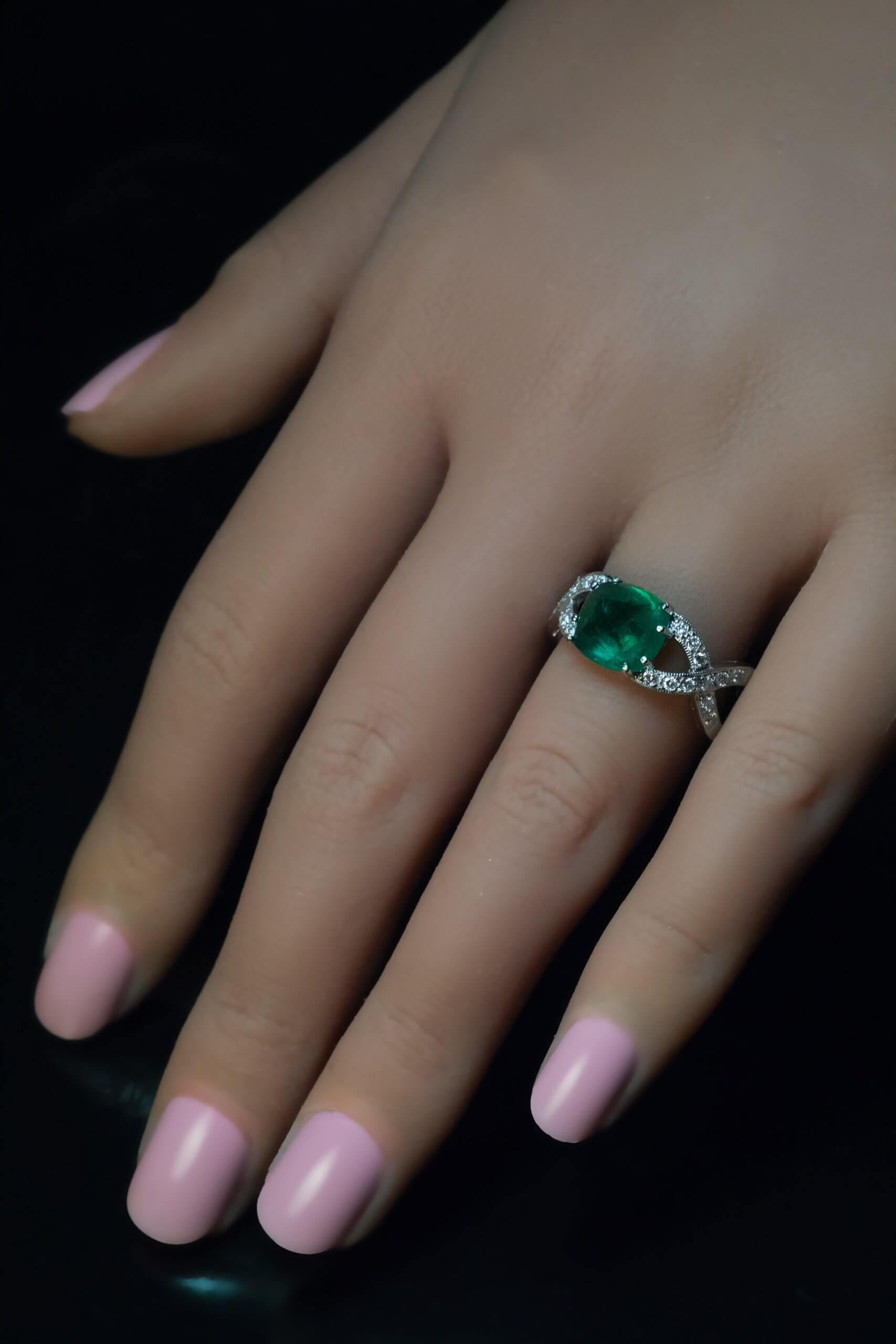 This contemporary 18K white gold ring features a 3.45 ct sugarloaf cabochon cut Zambian emerald of a very fine blueish green color. The emerald is flanked by eternity motif shoulders set with diamonds.  Total emerald weight is 3.45 carats. 