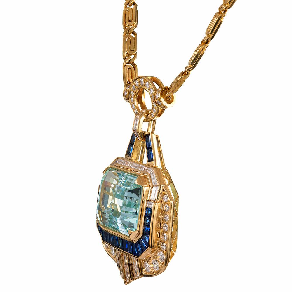 The design of this absolutely spectacular pendant is centered upon a 34.60 carats emerald cut aquamarine. The substantial stone glistens with sea-colored allure from its surrounding frame of baguette- and round diamonds with intense blue sapphires
