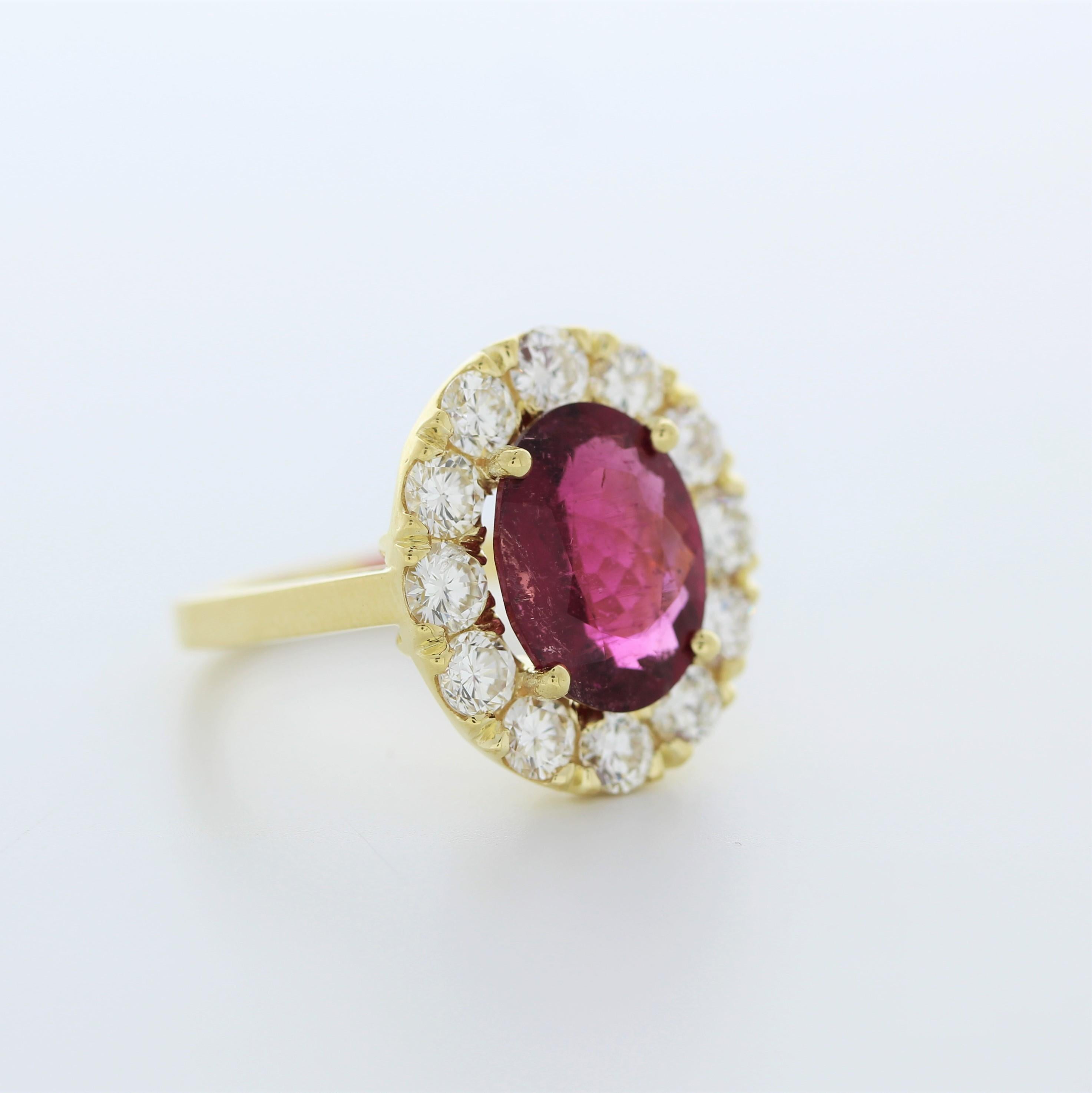 The fashion ring features a 3.48-carat oval-cut rubellite gemstone set in 18 karat yellow gold, accented by 12 round-cut diamonds with a total weight of 1.7 carats. The combination of the vibrant rubellite and sparkling diamonds against the yellow