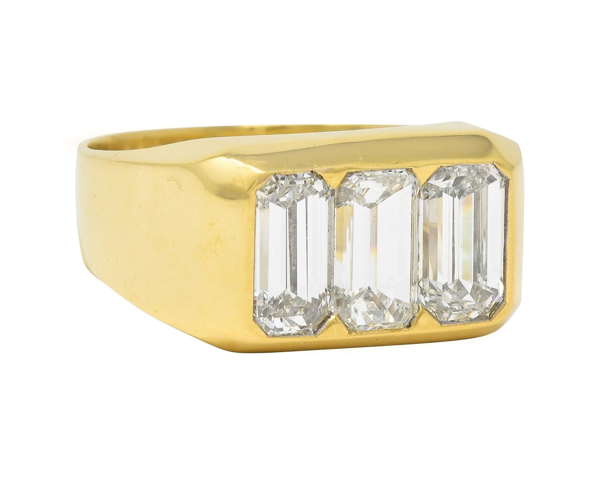 Centering three emerald cut diamonds flush set east to west in rectangular form head
Weighing approximately 3.48 carats total - H color with VS2 clarity
Completed by subtle facet motif surround
With high polish finish
Tested as 18 karat gold 
Circa: