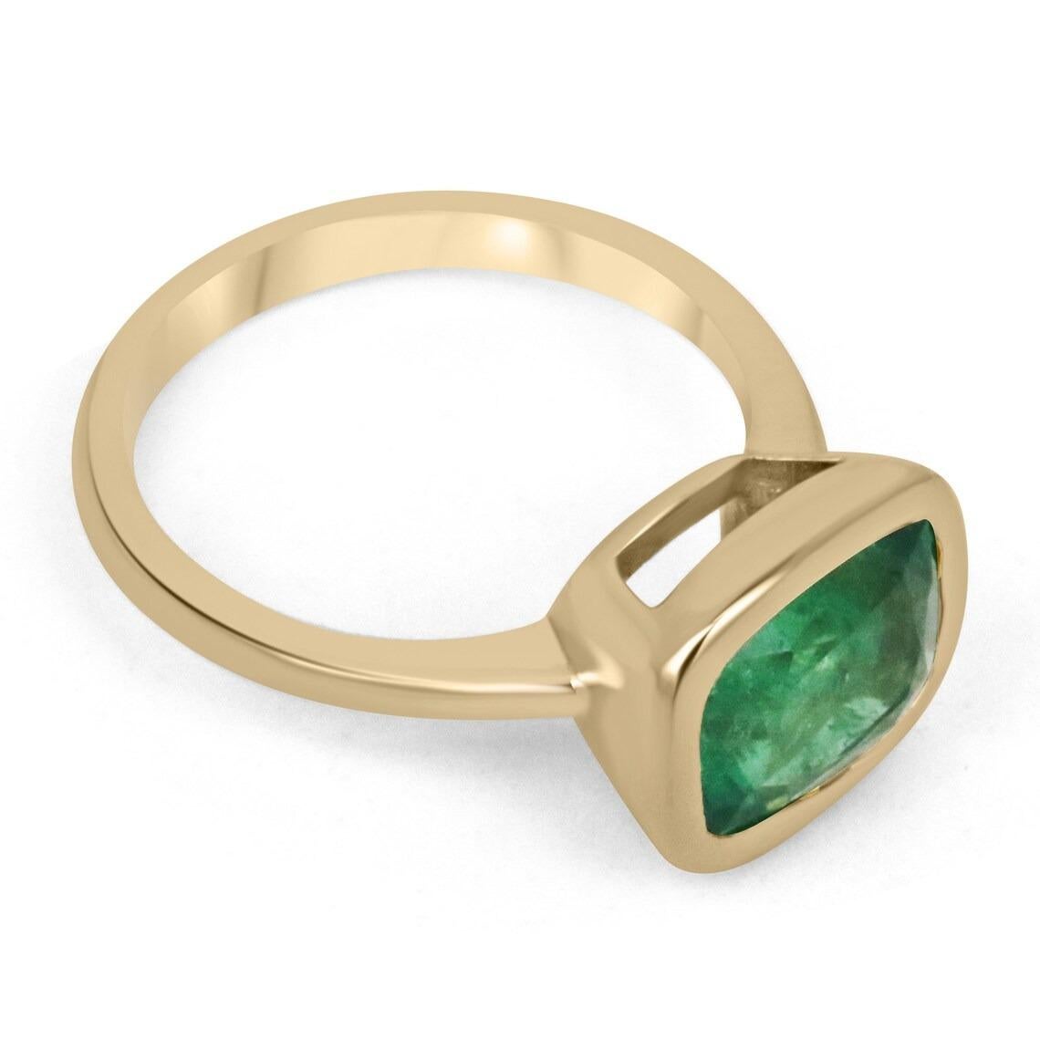 Displayed is a medium-dark green Zambian emerald, solitaire, cushion cut bezel ring in 18K yellow gold. This gorgeous solitaire ring carries a full 3.48-carat emerald in a sleek bezel setting. The emerald has incredible clarity and luster. This