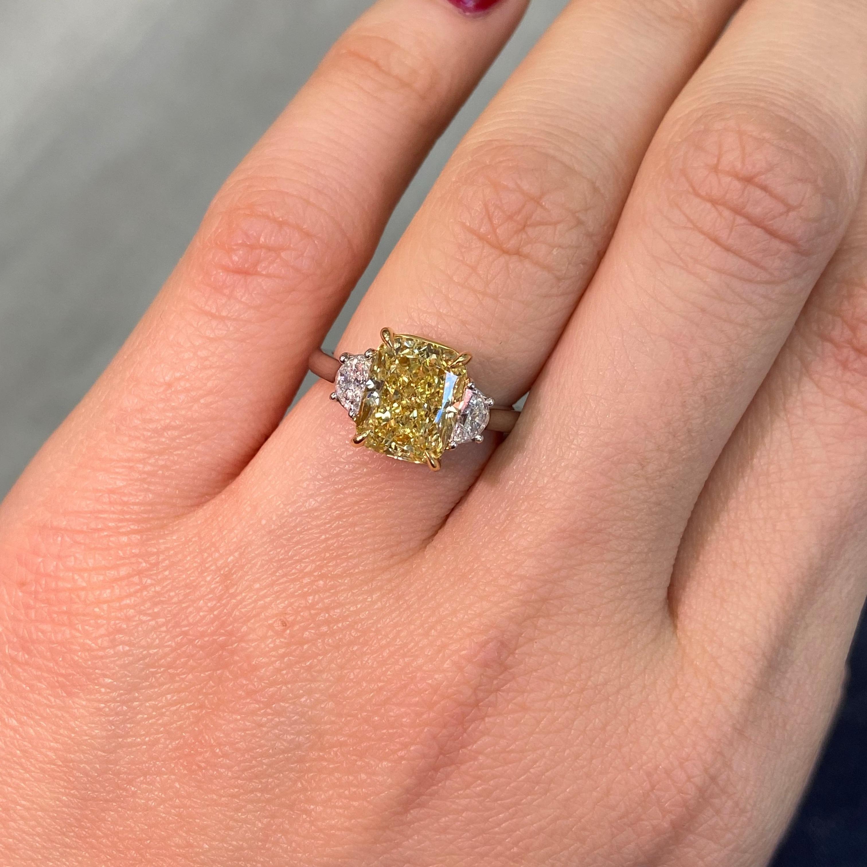Este exquisito anillo de compromiso de 3,48 quilates de tres piedras Amarillo Fancy es una asombrosa fusión de rara belleza y artesanía experta. En su centro hay un diamante Fancy Yellow de talla cojín alargada con certificado GIA y claridad VVS1,