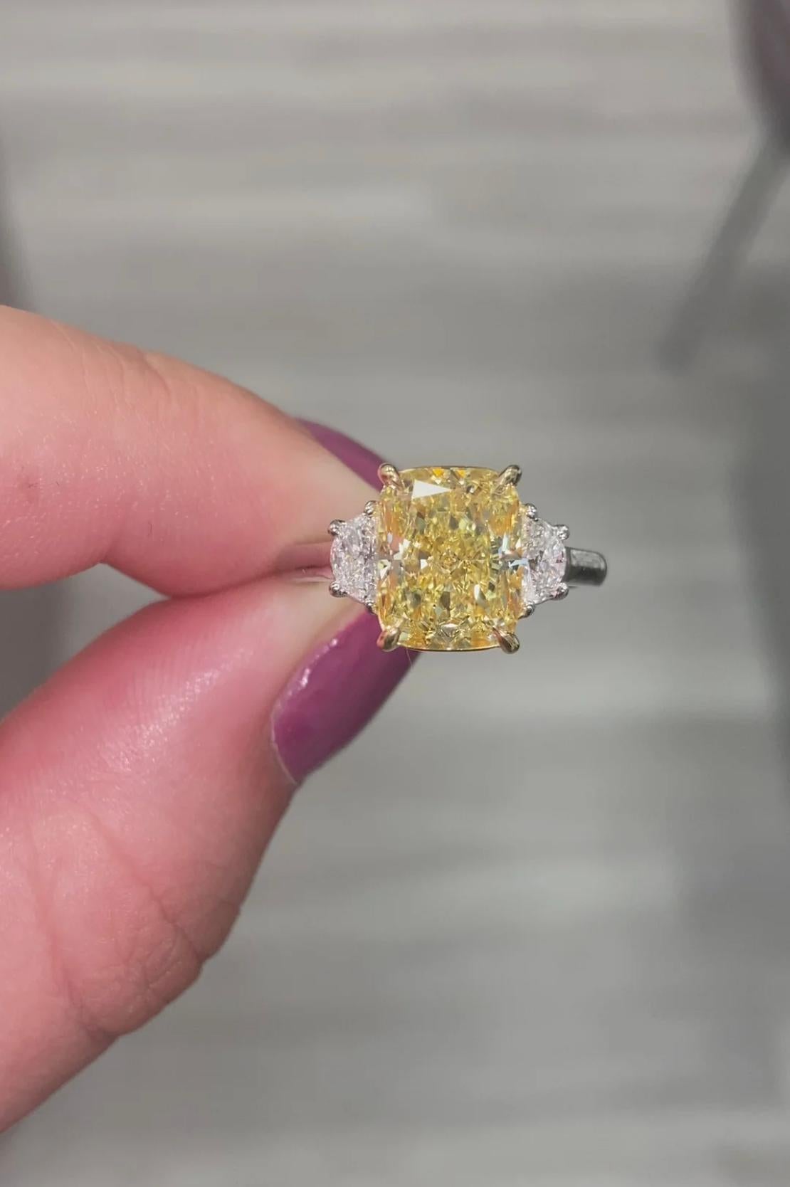 Beautiful fancy yellow elongated cushion cut with VVS clarity and excellent cutting in a three stone ring made of platinum yellow gold and colorless trapezoids
This piece can be viewed before purchase in our showroom in NYC or at one of our retail