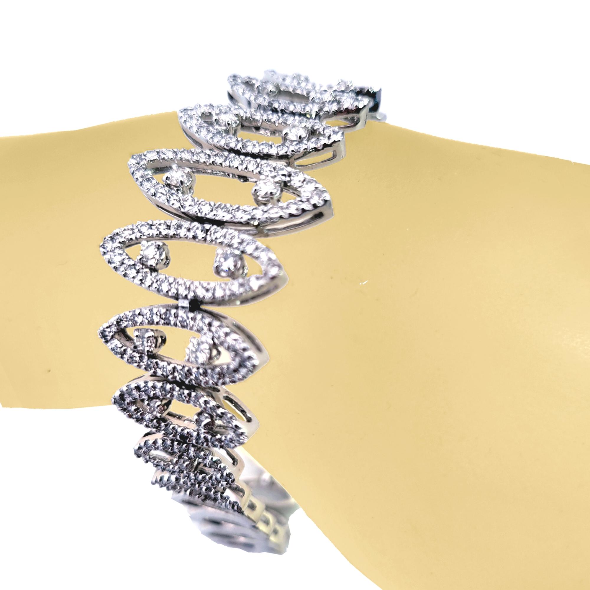 Dieses wunderschöne Diamantarmband ist aus 14K Weißgold gefertigt. Es ist 7 Zoll lang und etwa 25 mm  (1 Zoll) breit in der Mitte.  Die Diamanten sind im Pave Set gefasst und  Zacken gesetzt. Das Armband wird mit einem eingebauten Schloss und einem