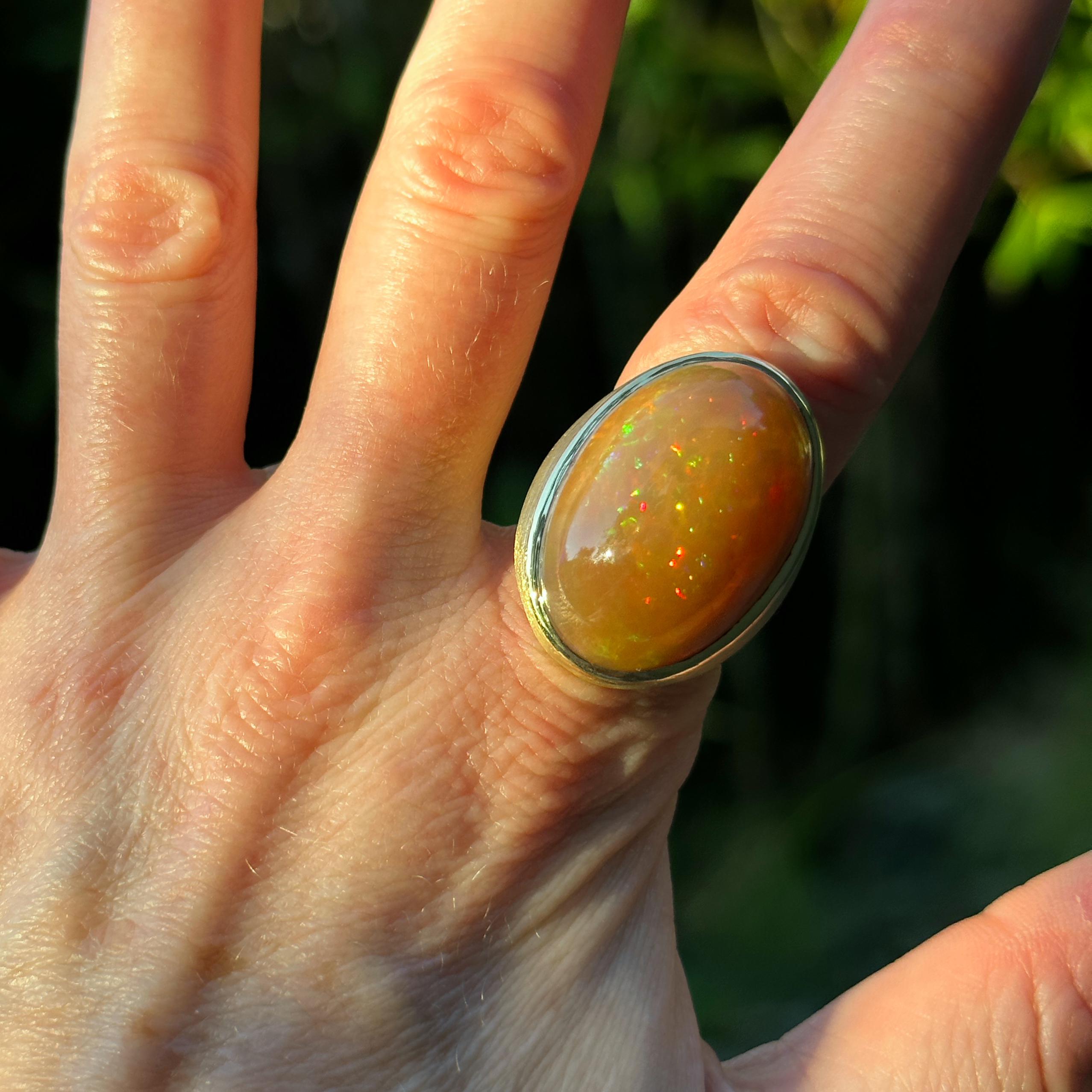 The body color of this huge Ethiopian opal is sort of a pastel orange, but green, yellow and red flashes abound.  The entire effect changes in every lighting situation.  Even in indirect natural light, when some orange opals tend to look soupy, this