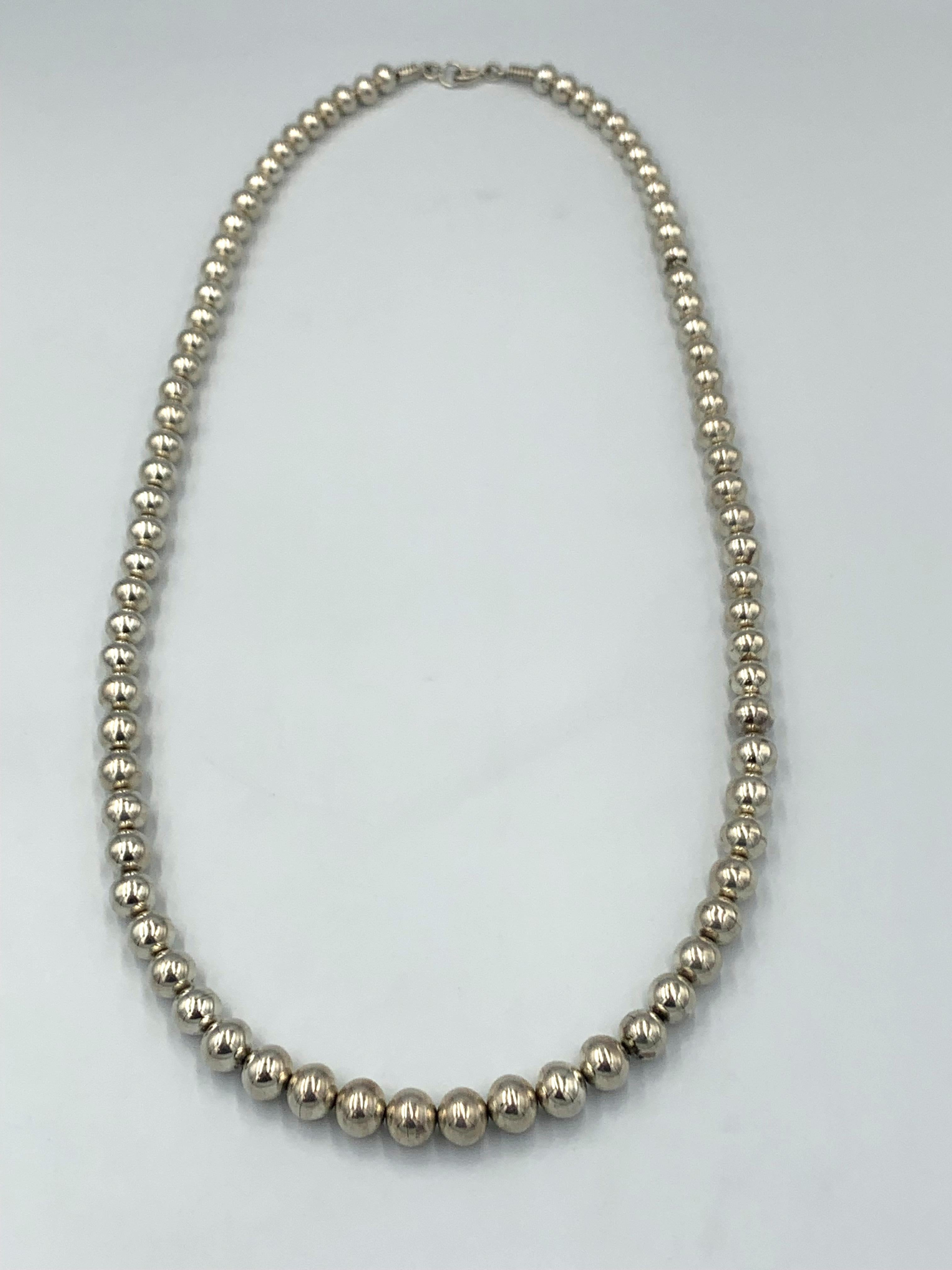 Collar de una sola hebra de plata de ley con cuentas de perlas navajo hechas a mano en tamaños graduados con un acabado pulido. 

Longitud del collar: 35
Diámetros de talón: 3/8