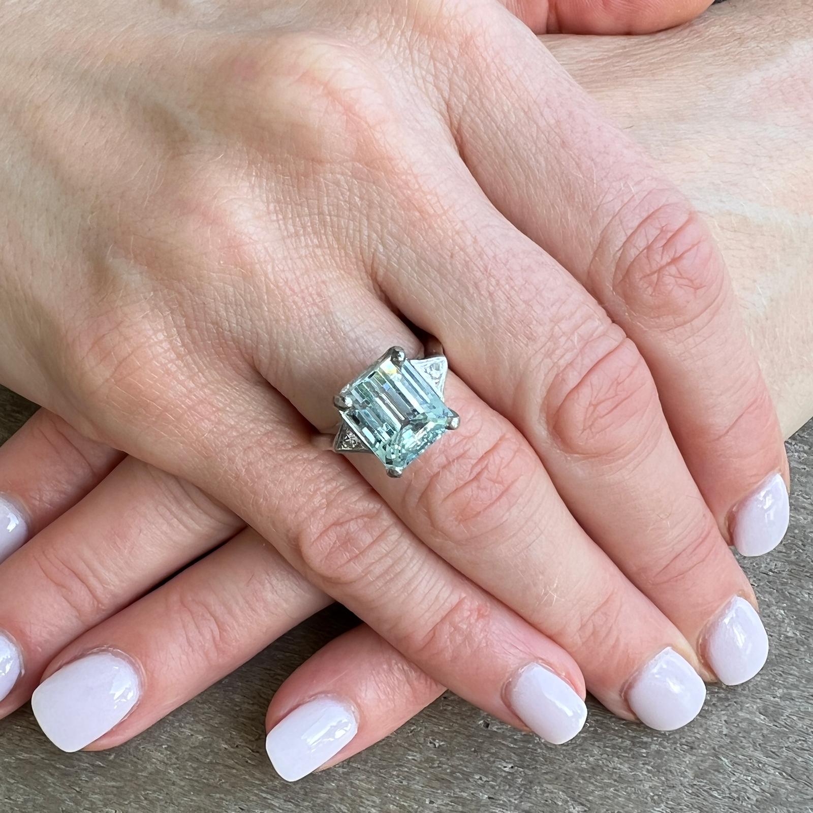 Beautiful natural aquamarine and diamond cocktail ring crafted in 14 karat white gold. The ring features an approximately 3.50 carat emerald cut natural blue aquamarine gemstone flanked with two round brilliant cut diamonds weighing approximately