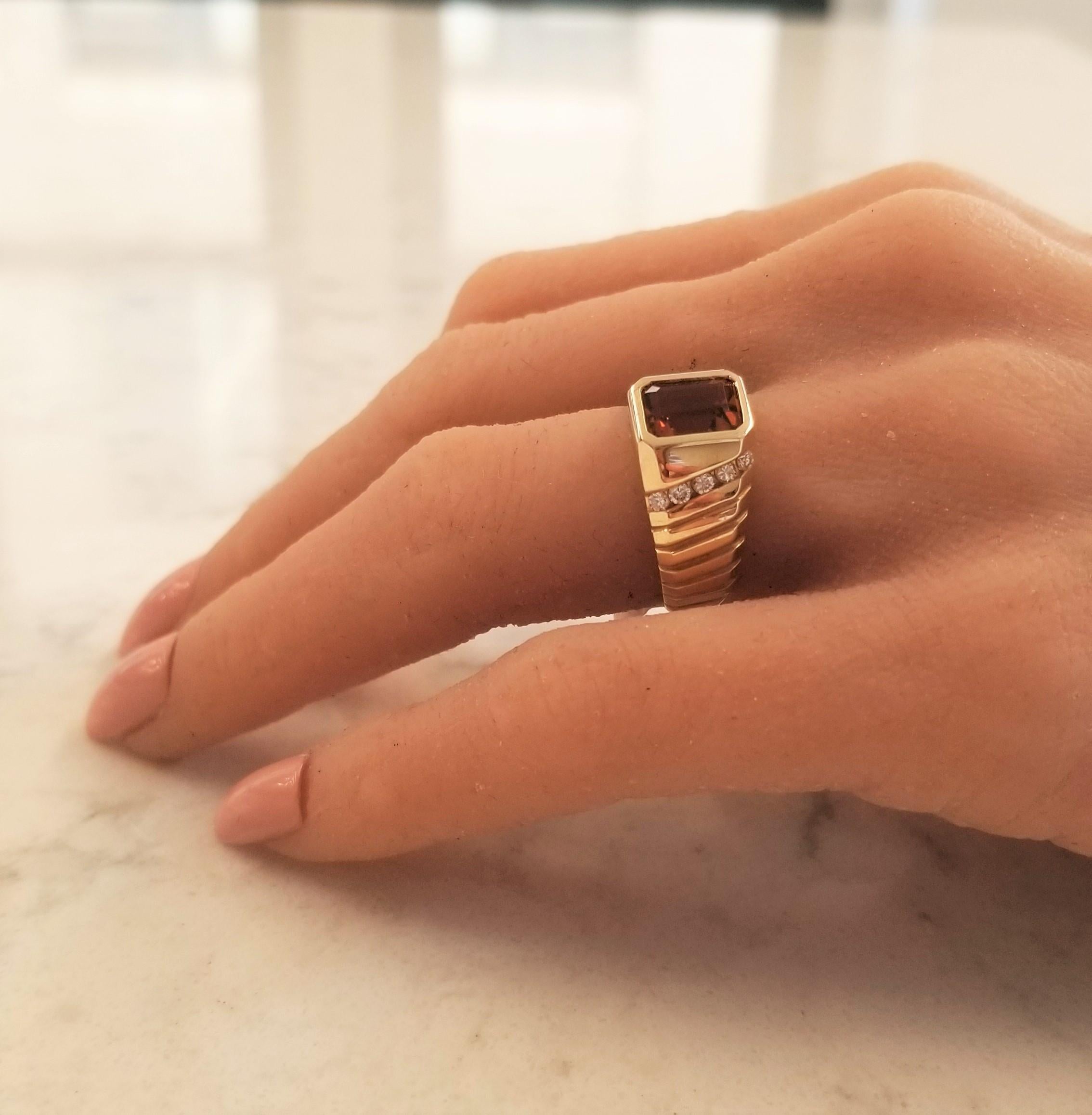 This ring features a 3.50 carat emerald cut Citrine measuring 8.9 x 7.0mm. The gem source is Brazil. Its color is dark orange. Its transparency and luster are excellent. The gem is accented by 10 sparkling round brilliant cuts, channel set, totaling