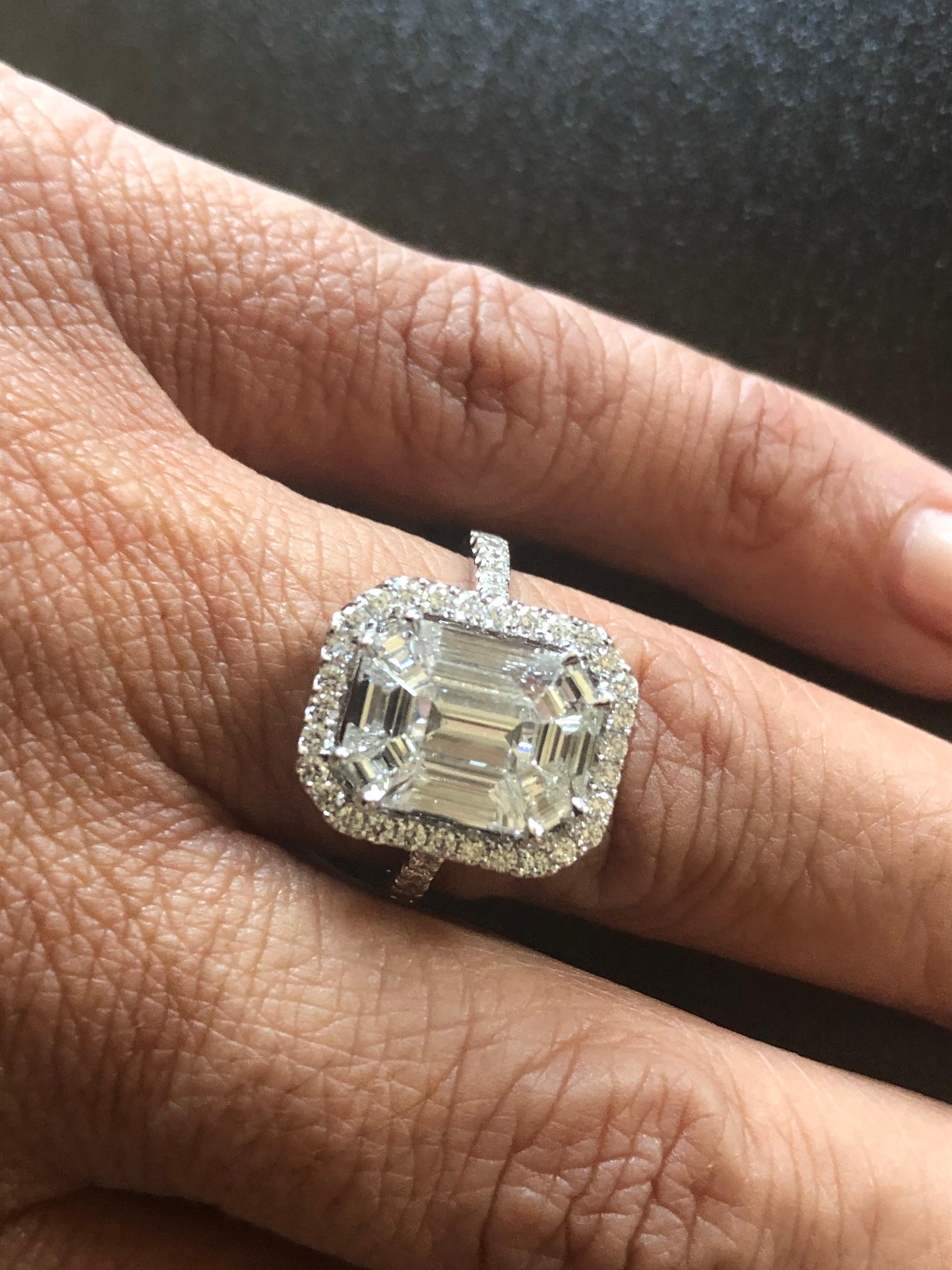 Baguette-:: Smaragd- und trapezförmige Diamanten in einer Illusion:: die das Aussehen eines einzelnen 9-karätigen Steins im Smaragdschliff erzeugt. Der Ring ist mit einem Halo aus runden Diamanten und an der Seite des Rings besetzt. Der Ring ist in