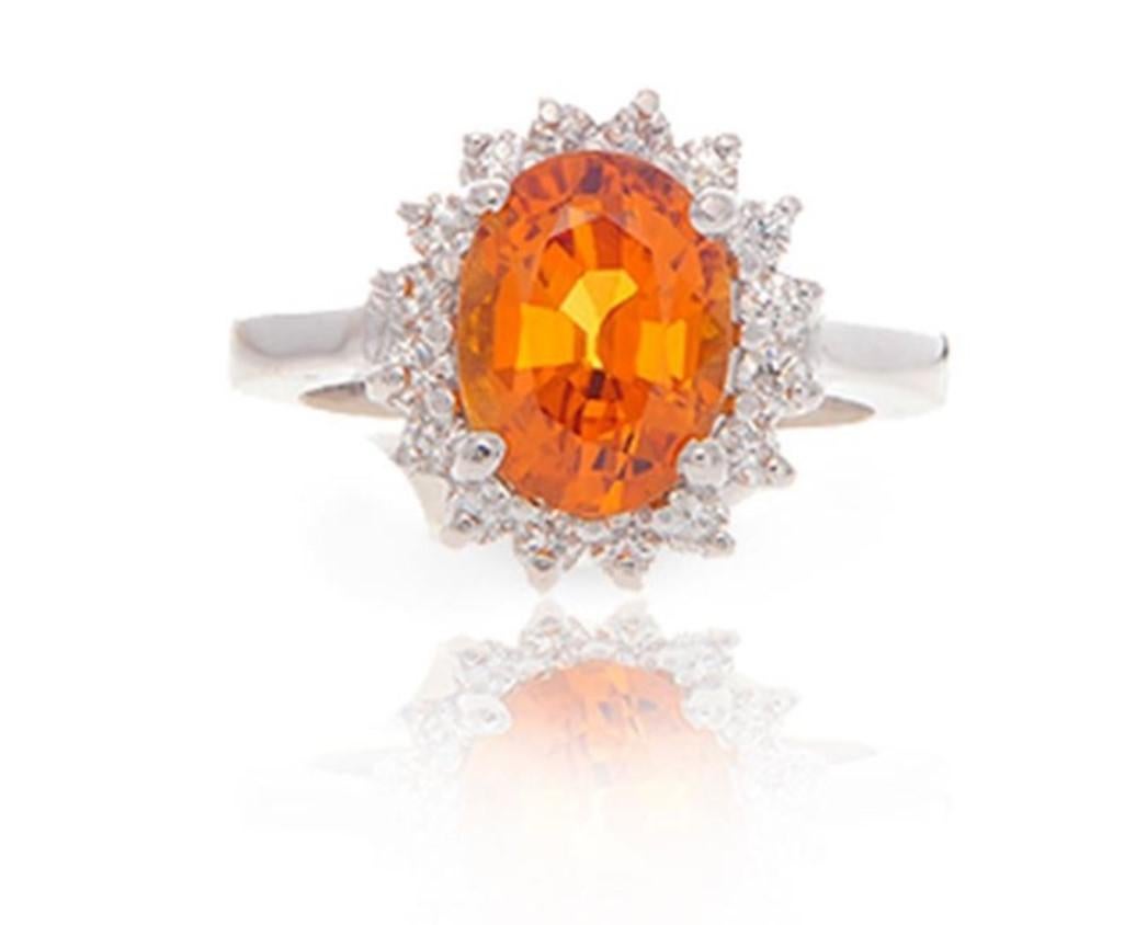 Classic Style 3.50 Carat Heated Oval Cut Natural Orange Sapphire Precious Gemstone mounted in a 14 Karat White Gold with Diamond Halo Ring.
Total Carat Weight on the ring is 4.06.
The large Heated Oval Shaped Orange Sapphire Gemstone has a deep and