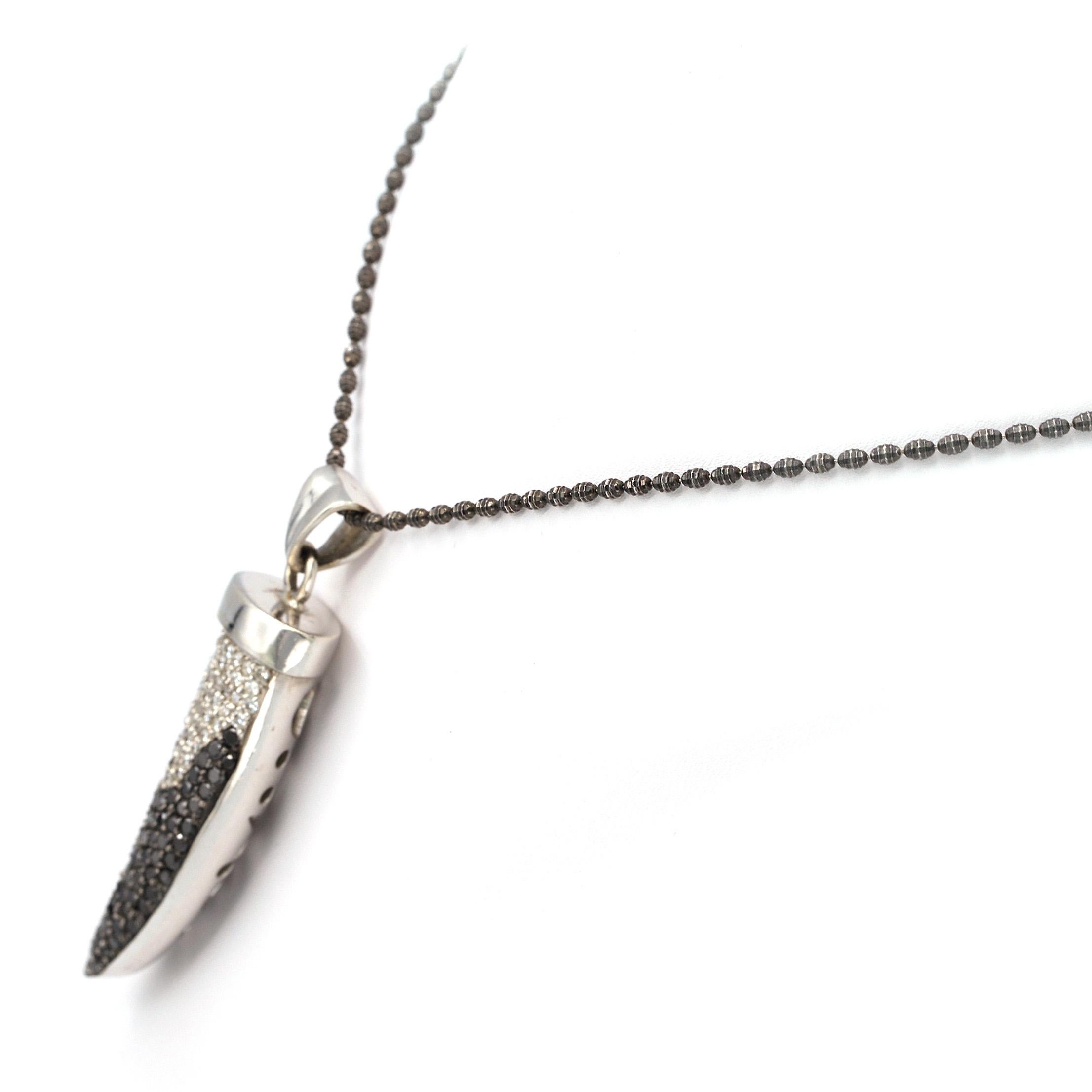 This Pendant has approximately 3.50 carats of black and white diamonds in this tooth shaped design. It contains approximately 57 white diamonds and 59 black diamonds. 
The pendant comes with a Black Rhodium Plated  14K chain that measures 39cm long.
