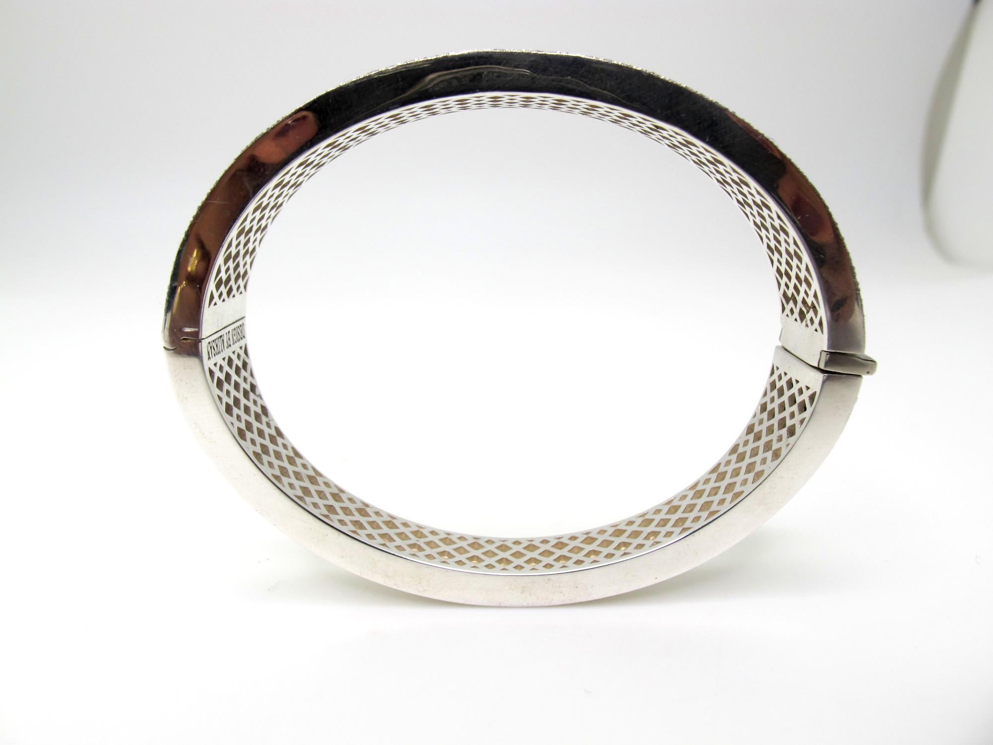 This beautiful sterling silver bangle bracelet is hand engraved with an elegant and ornate scroll design set with 3.50 carats of brilliant, sparkling diamonds! The stippled, blackened background showcases the intricate diamond-studded details,