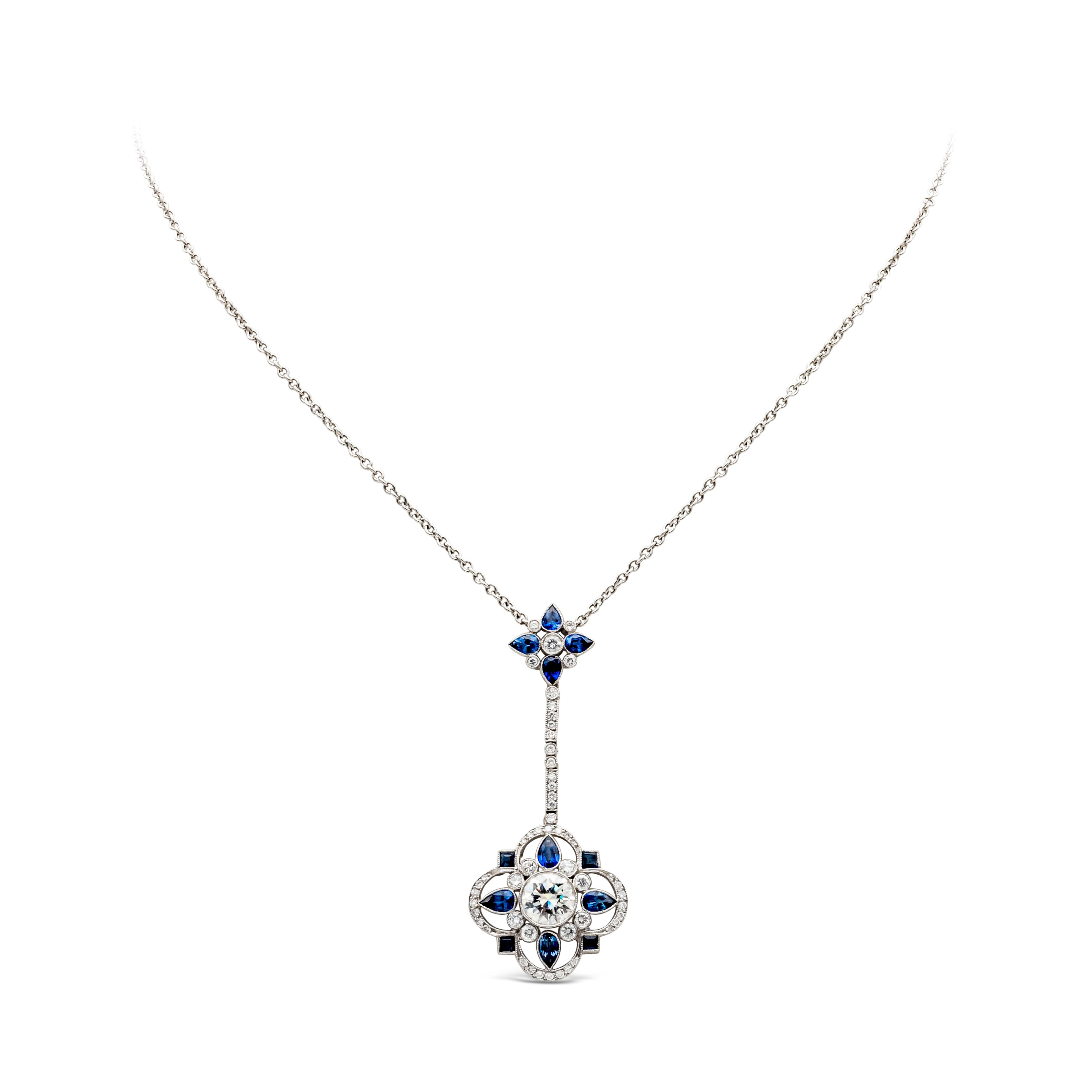 Set with a 1.38 carats round brilliant diamond center stone accented by 4 pear shape blue sapphires on each corner. Each sapphire is spaced by round cut diamonds in an open-work design. Pendant spaced by a single line metal set with round cut