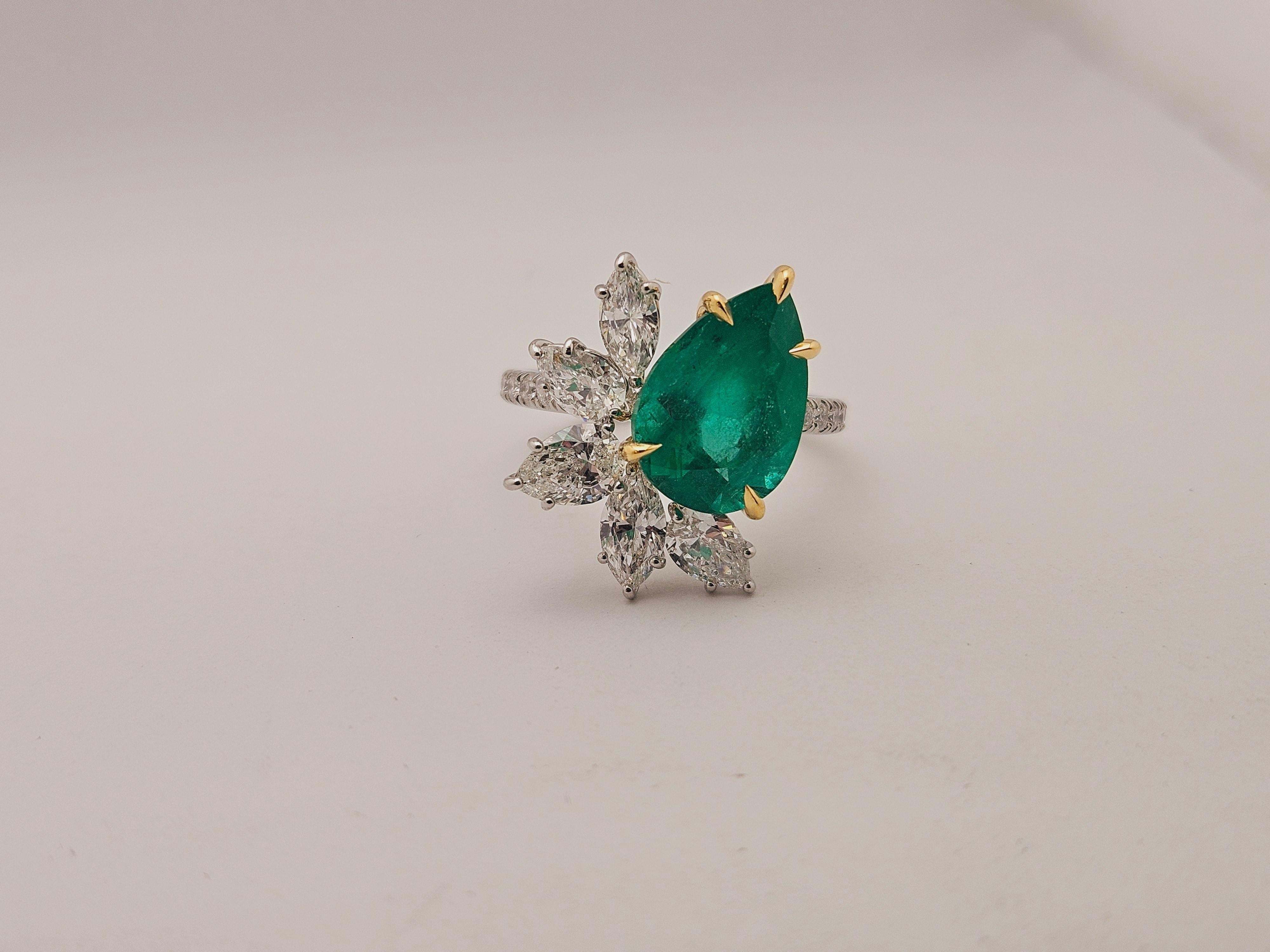 Il Columbian Emerald Cluster Ring è un pezzo straordinario, caratterizzato da uno smeraldo colombiano a forma di pera da 3,50 carati con una ricca tonalità verde, certificato dalla GIA per verificarne l'autenticità. Lo smeraldo è incastonato in oro