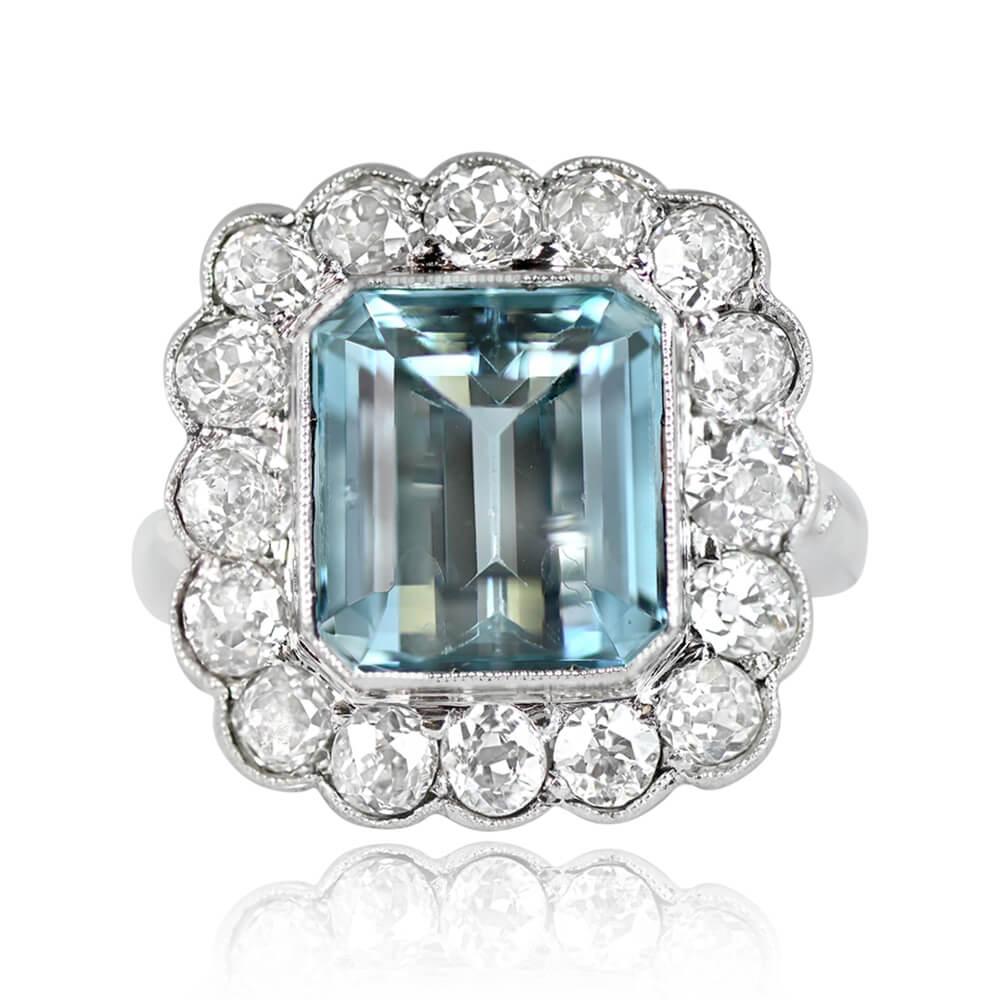 An exquisite ring featuring a 3.50-carat emerald cut aquamarine at its center, set in a bezel. Surrounding the aquamarine is a halo of old mine-cut diamonds with H color and VS1-SI1 clarity, complemented by additional old mine-cut diamonds set