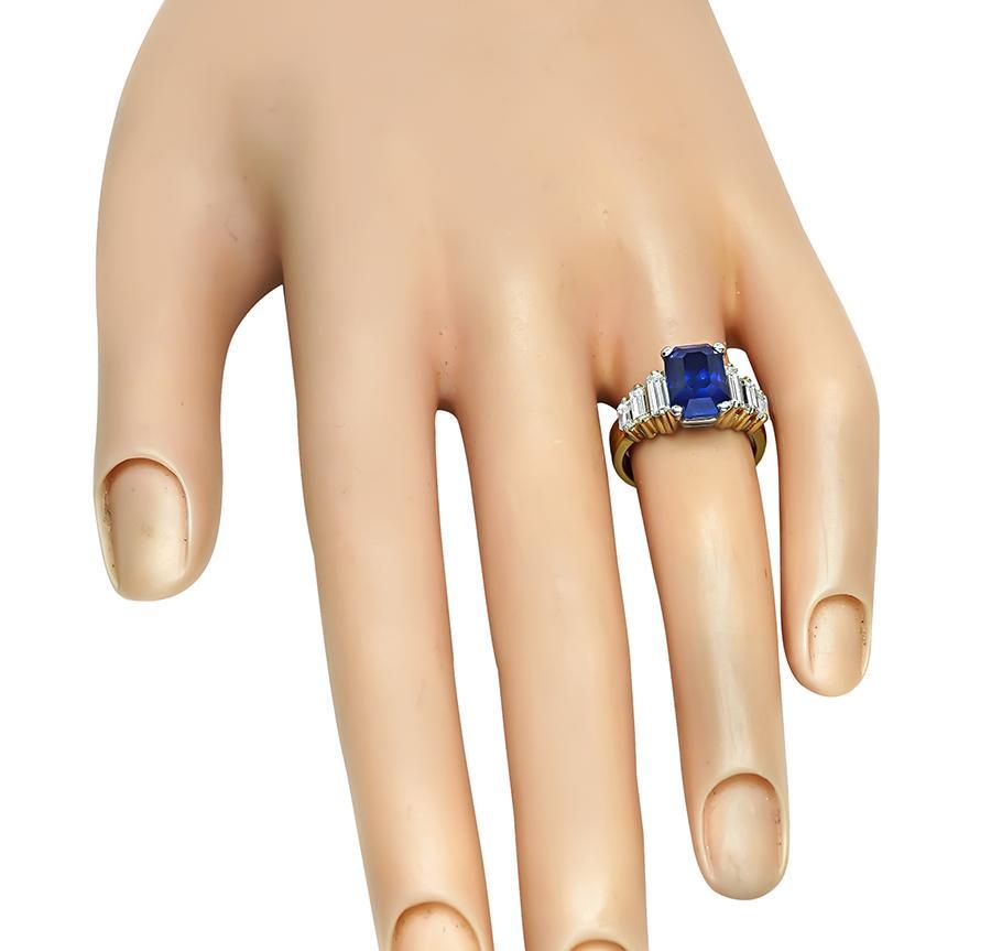 Questo è un favoloso anello di fidanzamento in oro giallo e bianco a 18 carati. L'anello è centrato da un delizioso zaffiro taglio smeraldo che pesa circa 3.50 carati. Lo zaffiro è accentuato da scintillanti diamanti taglio baguette del peso di