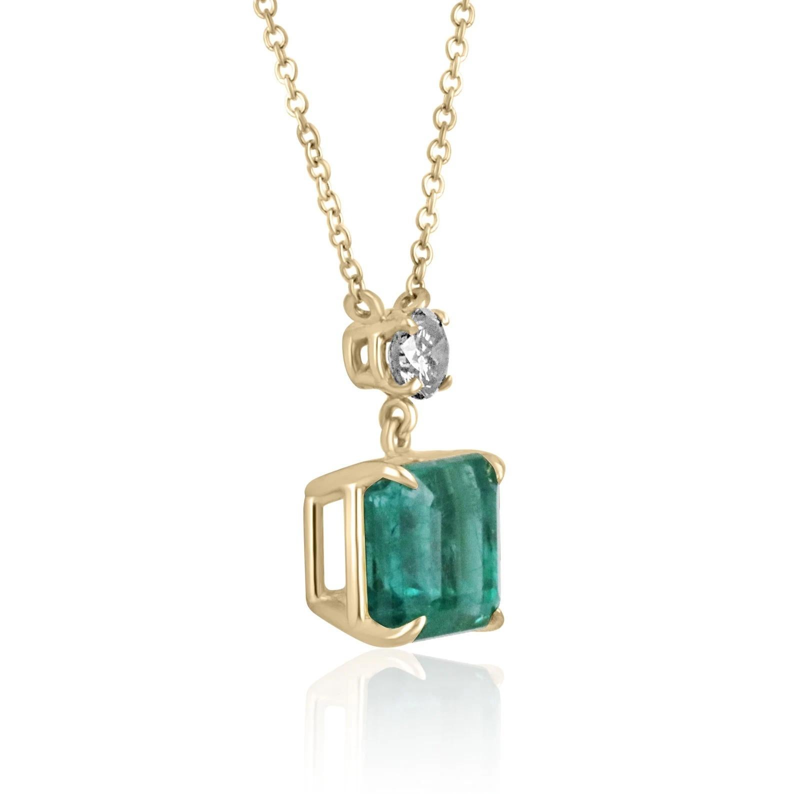 Featured here is a stunning, rich bluish-green emerald and round diamond necklace handmade in fine 14K yellow gold. Displayed is a lustrous, medium-rich green emerald with very good transparency, accented by a simple secure four-prong 14K mount,
