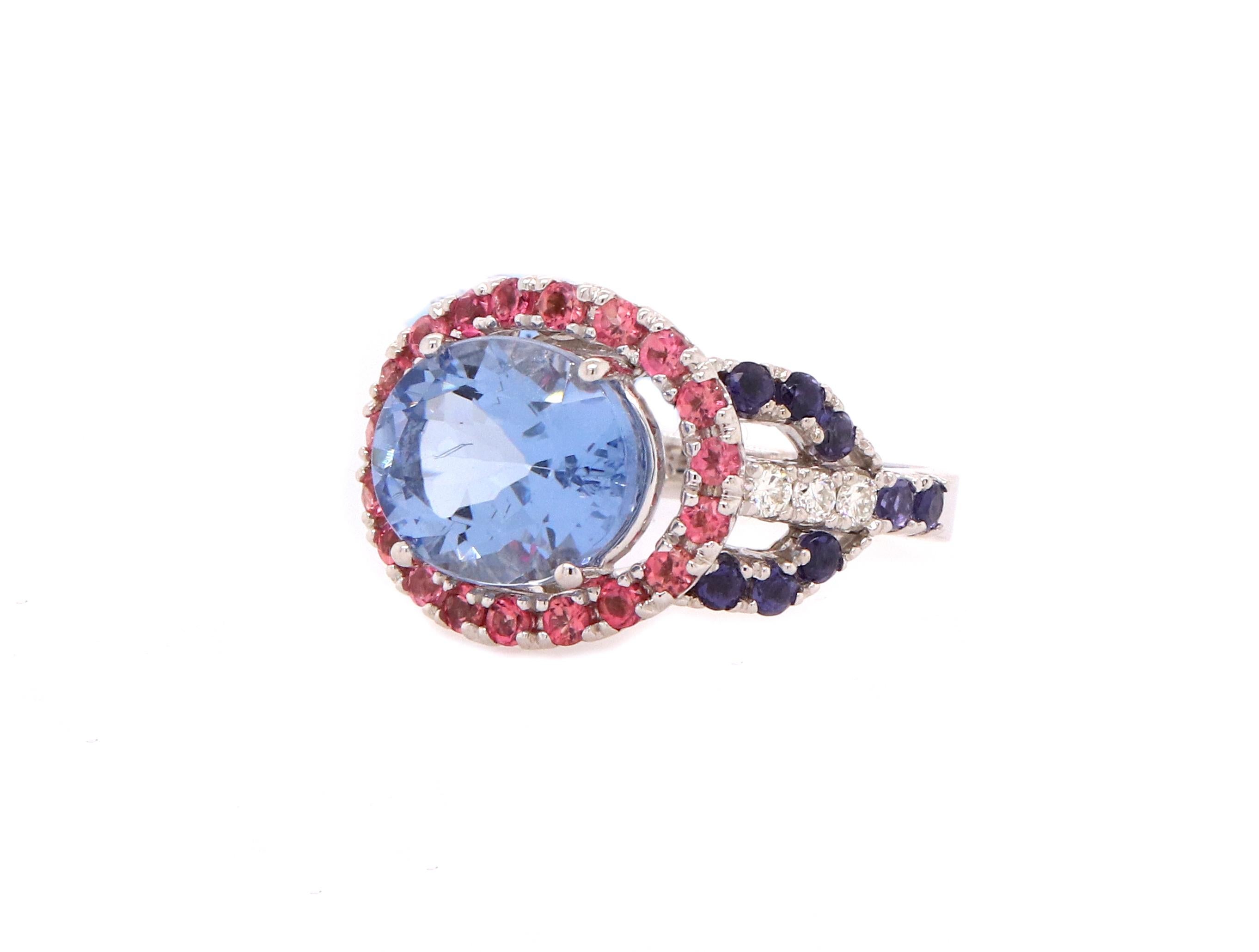 Material: 14k White Gold 
Center Stone Detail:  1 Oval Blue Beryl at 3.52 Carats - Measuring 9 x 11 mm
Mounting Stone Details:  19 Round Pink Tourmalines at 0.59 Carats
Mounting Stone Details:  16 Round Iolites at 0.56 Carats
Diamond Details: 6 