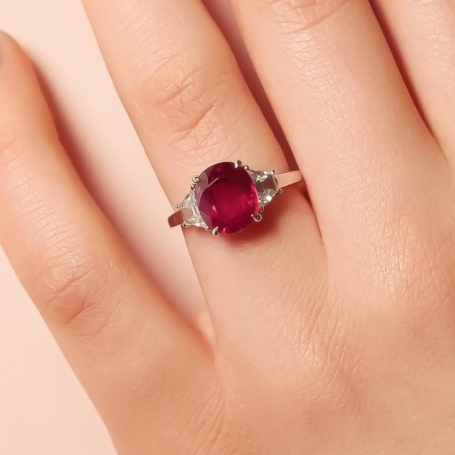 Elegance meets glamour in this spectacular three-stone piece from the Haruni family. At its centre is a captivating bright red ruby, hailing from Mozambique and cut in a sophisticated oval shape. To both sides of the stone are gleaming, trapeze cut
