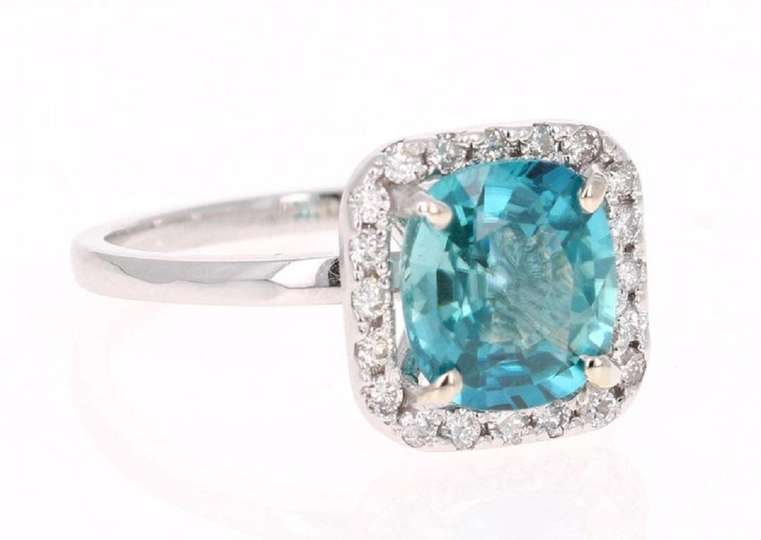 A Dazzling Blue Zircon and Diamond Ring! Blue Zircon is a natural stone mined in different parts of the world, mainly Sri Lanka, Myanmar, and Australia. 

This ring has a Cushion Cut Blue Zircon that weighs 3.29 carats and is surrounded by 20 Round