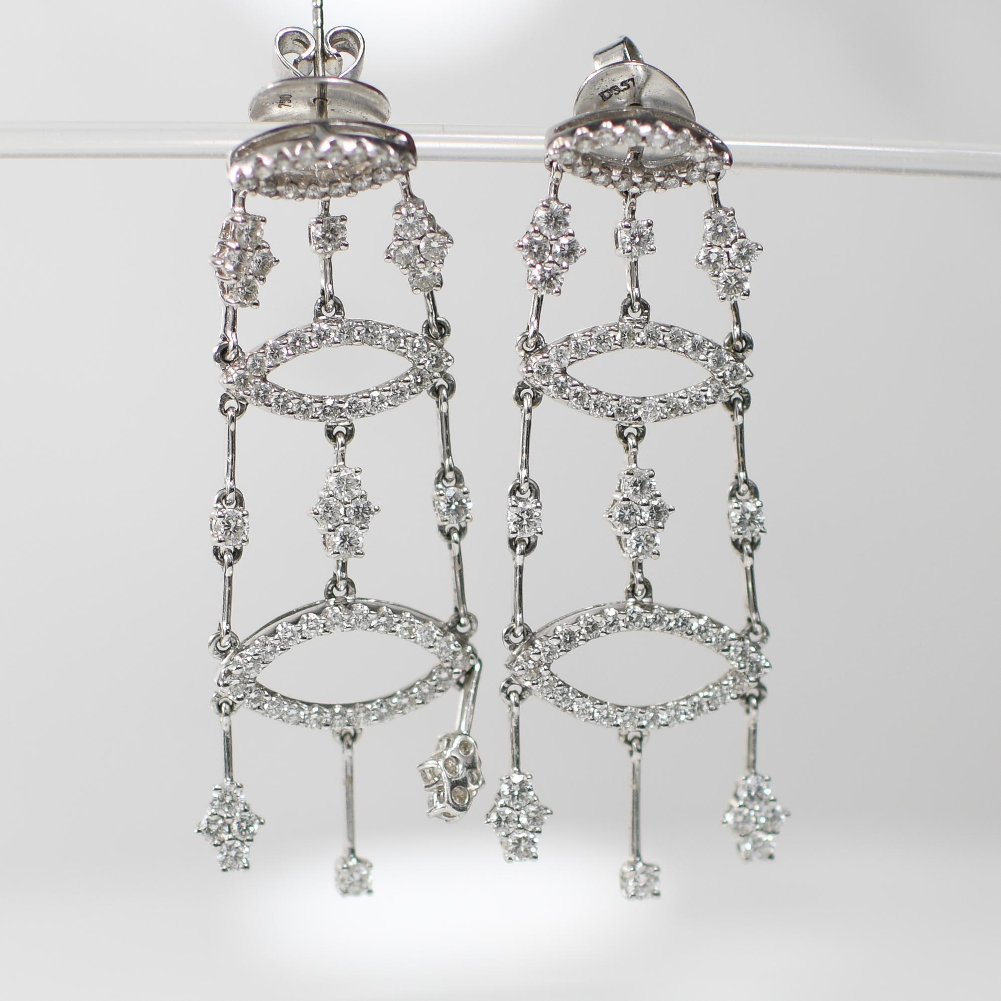 Elevate any ensemble with these resplendent chandelier-style earrings, meticulously crafted in luminous 18K white gold. Cascading in three tiers, each adorned with scintillating round brilliant-cut diamonds, they exude timeless elegance and