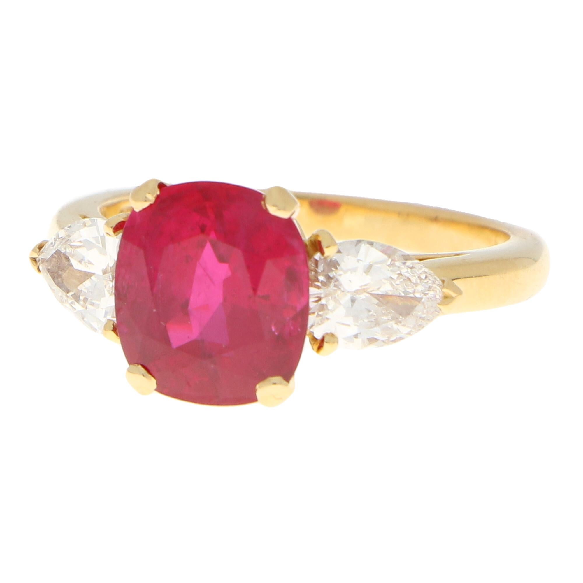 A truly stunning certificated Burmese ruby and diamond three stone engagement ring set in 18k yellow gold.

The ring is centrally set with a beautiful 3.58 carat hand-cut cushion shaped Burmese ruby which is securely four claw set in an elegant open