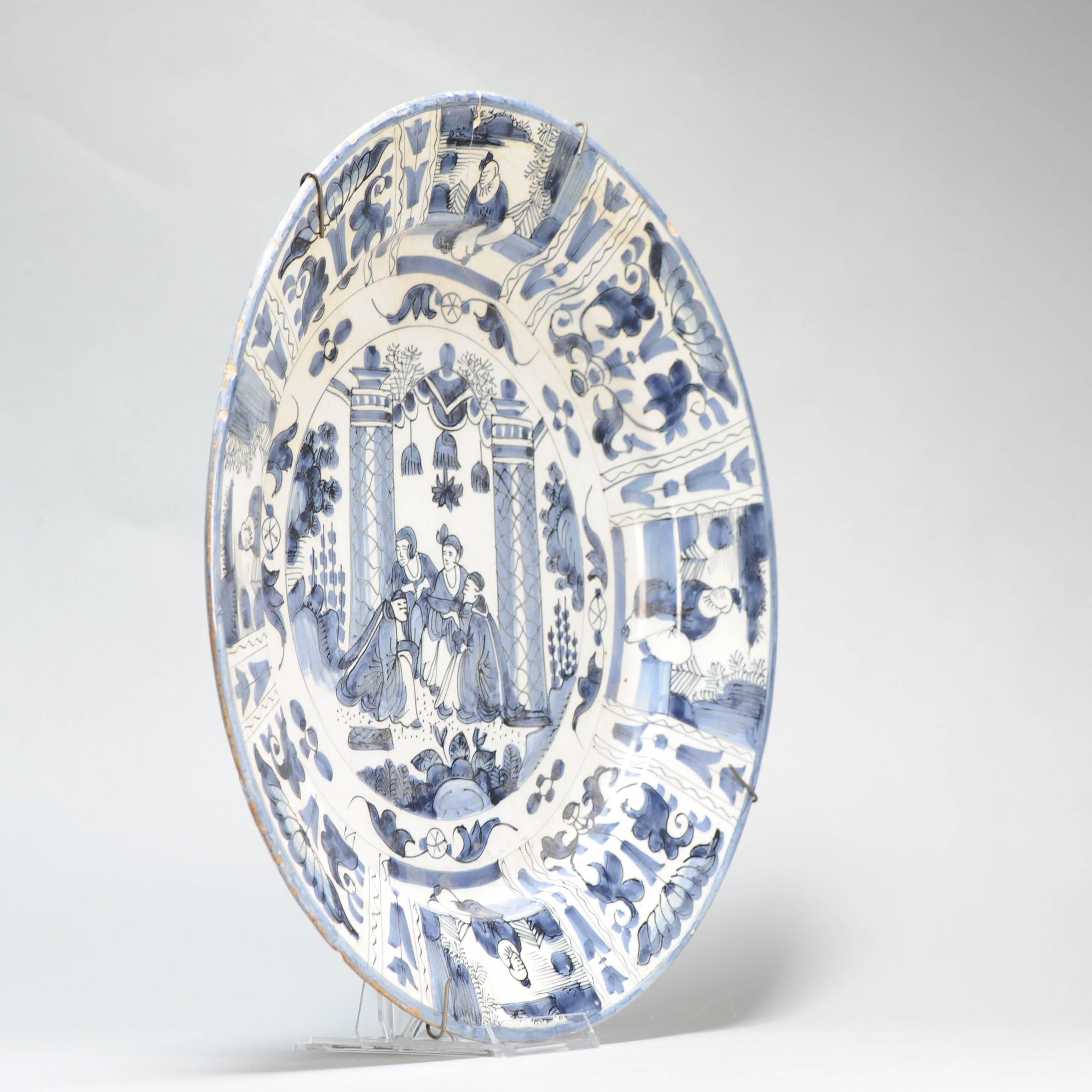 Earthenware dish with a flat rim.
Decorated in different shades of blue on a white tin glaze. Central scene of a group of figures in a garden scene. The border also with figures and flowers. These kind of dishes were made after Chinese Kraak