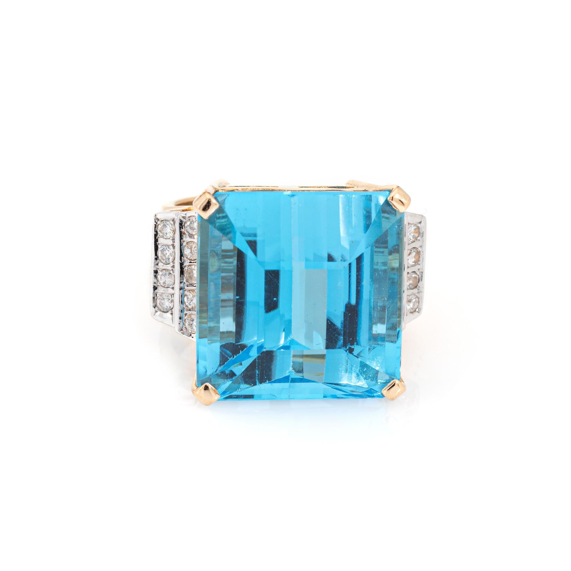Stylish and finely detailed blue topaz & diamond cocktail ring crafted in 14 karat yellow gold (circa 1970s to 1980s).

Emerald cut blue topaz measures 17.5mm x 17mm (estimated at 35 carats). Diamonds total an estimated 0.18 carats (estimated at L-M