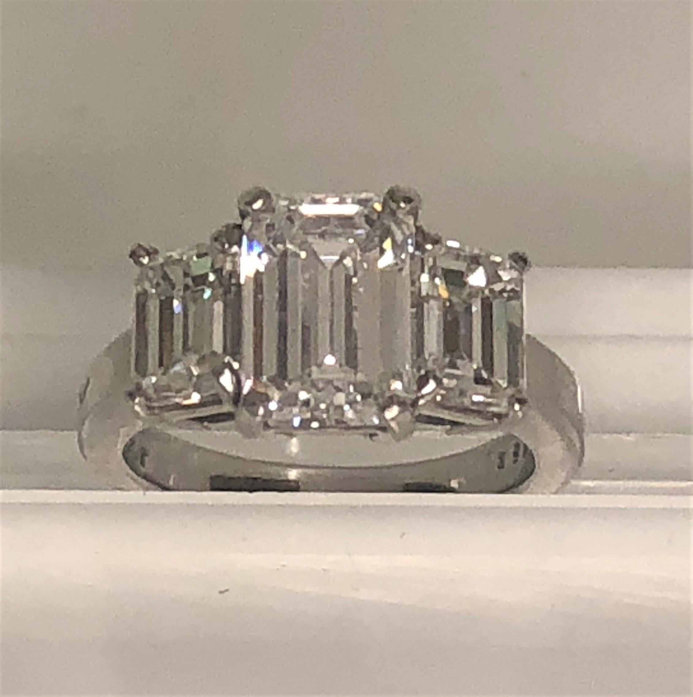 The ring SPARKLES!!  
Three near colorless emerald cut, prong set diamonds.
Center diamond is approximately 2.06 ct, VS2 clarity, E color (colorless!) with GIA certificate.
Side diamonds are approximately .80 ct each, VS-SI clarity, E-F color.
Band