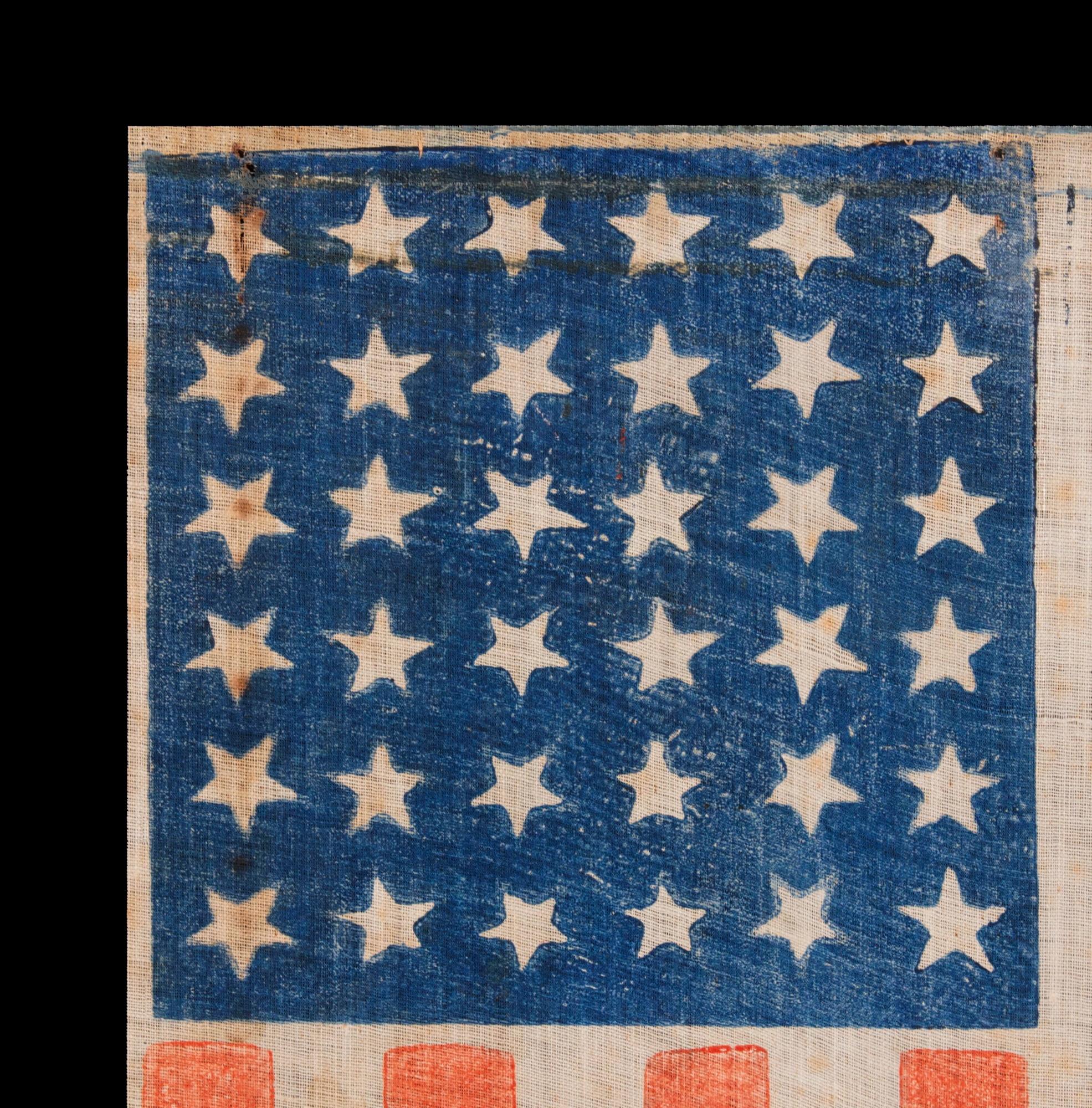 36 STAR ANTIQUE AMERICAN PARADE FLAG, WITH STARS THAT ALTERNATE IN THEIR VERTICAL POSITION FROM COLUMN TO COLUMN AND ROW-TO-ROW, PRINTED ON AN ESPECIALLY INTERESTING LENGTH OF COARSE COTTON WITH A CRUDE WEAVE THAT RESULTS IN A VISUALLY COMPELLING