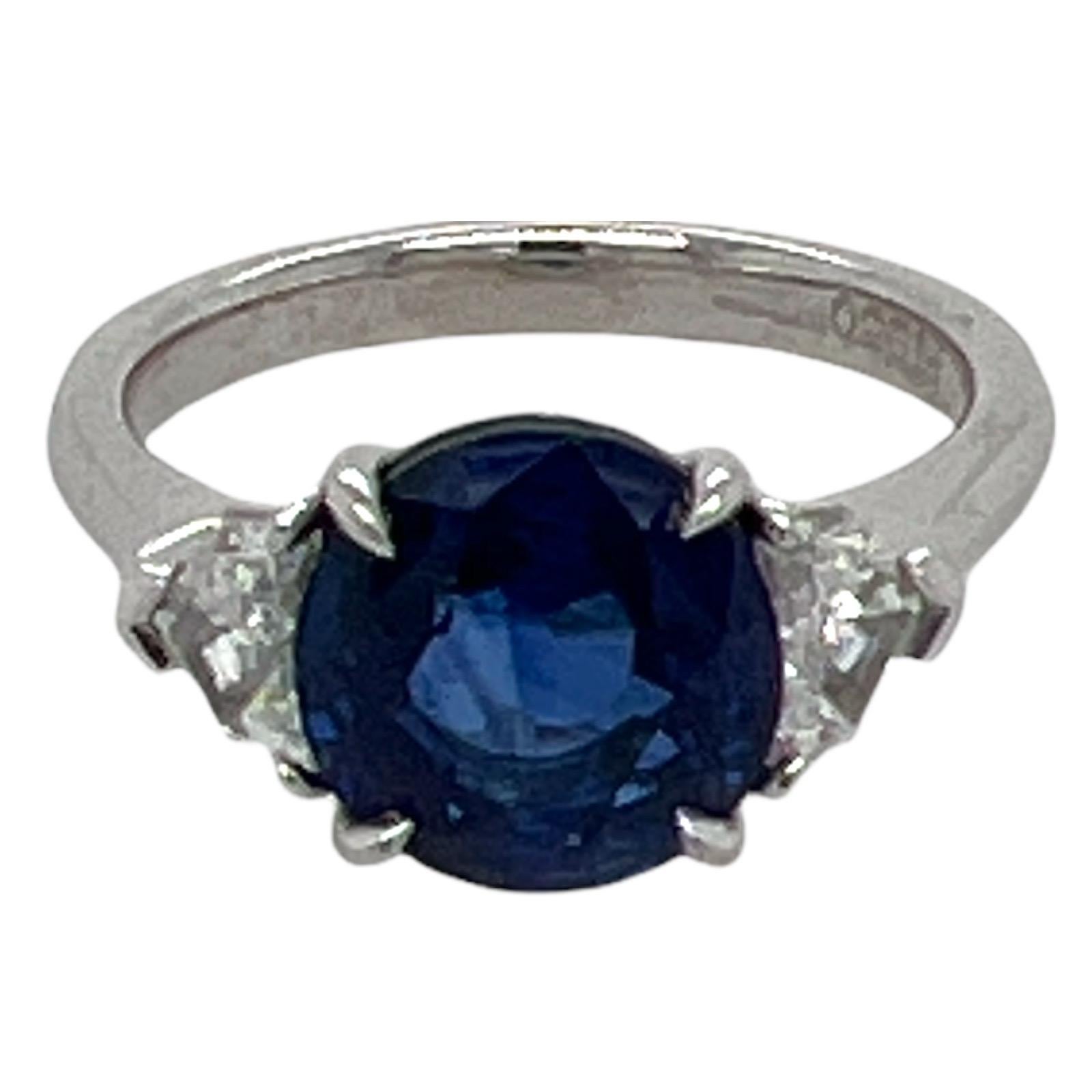 Atemberaubender Ring mit einem blauen Ceylon-Saphir und Diamanten, handgefertigt in Platin. Der Ring ist mit einem 3,60 Karat schweren, runden, lebhaften blauen Saphir besetzt, der von 2 Diamanten im Schildschliff flankiert wird. Die beiden