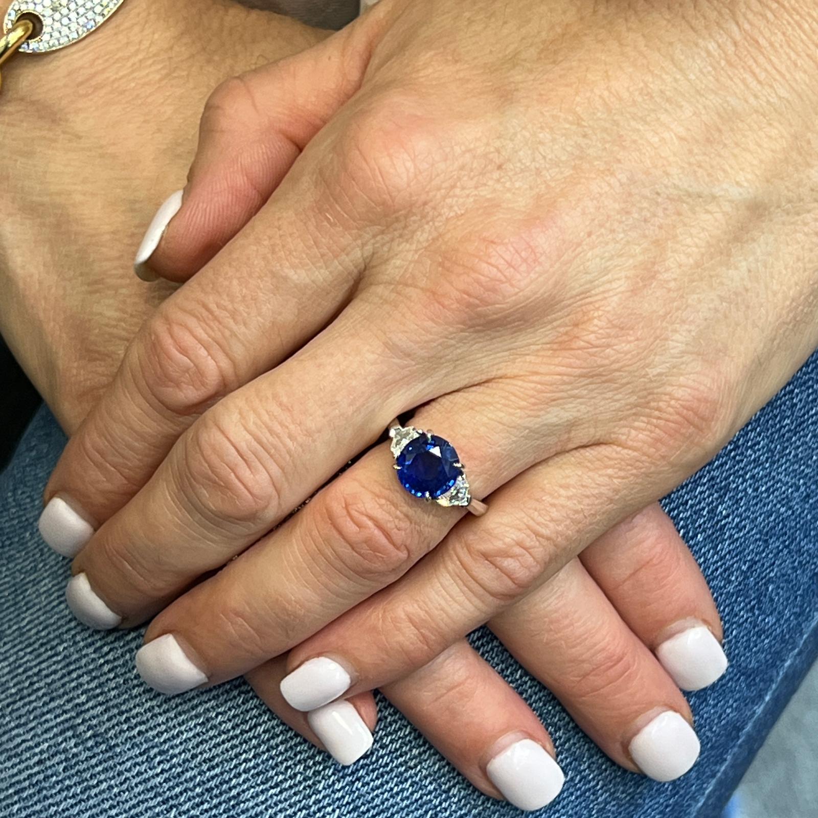 Atemberaubender Ring mit einem blauen Ceylon-Saphir und Diamanten, handgefertigt in Platin. Der Ring ist mit einem 3,60 Karat schweren, runden, lebhaften blauen Saphir besetzt, der von 2 Diamanten im Schildschliff flankiert wird. Die beiden
