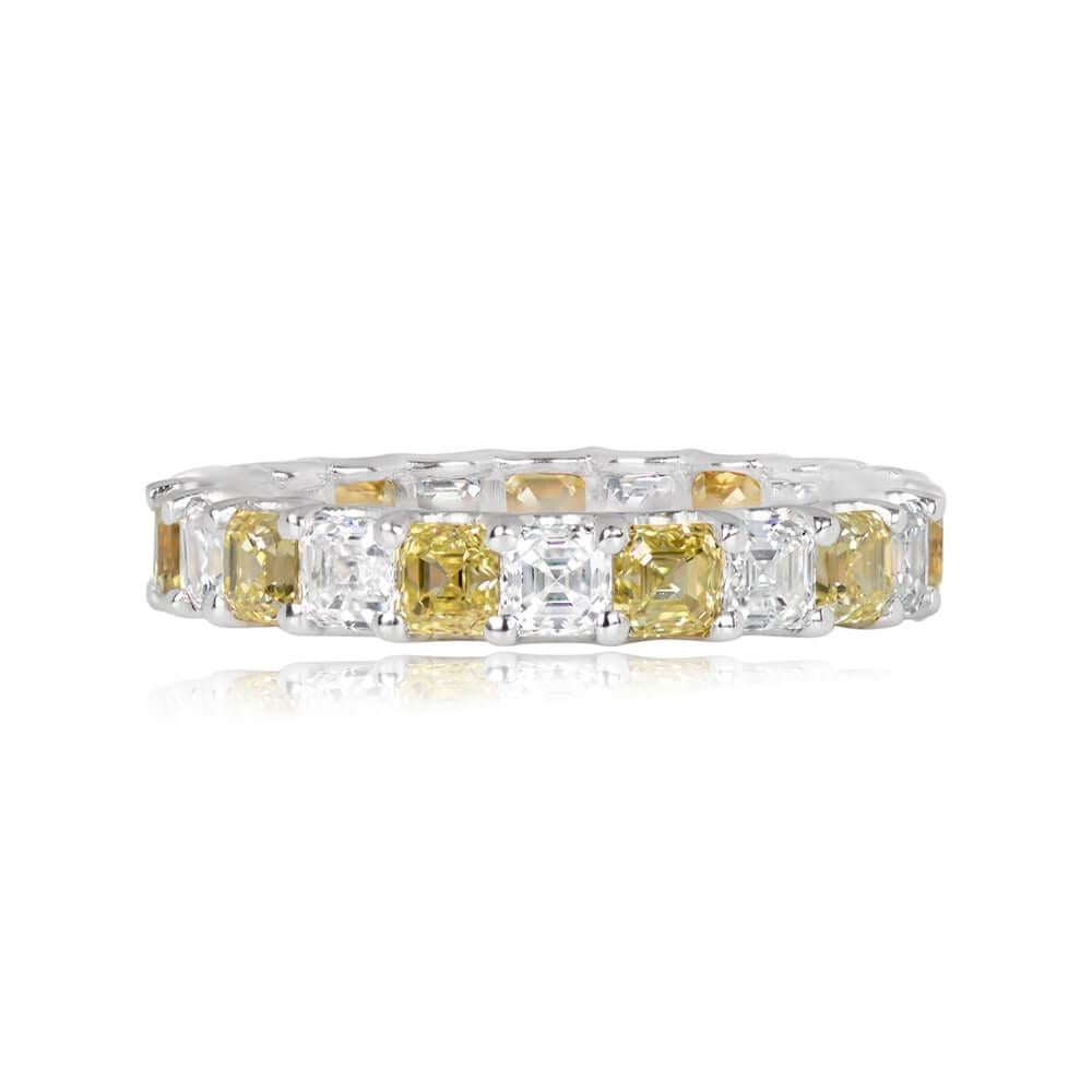 A captivating diamond eternity band featuring 3.60 carats of Asscher cut diamonds. The band showcases an exquisite alternating pattern with eleven Fancy Vivid Yellow and eleven D-E color Asscher cuts, securely held by prongs. The Fancy Yellow