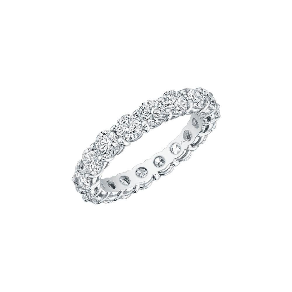 • Crafted in 18KT gold, this eternity band is made with 18 round brilliant cut diamonds, and has a combining total weight of approximately 3.60 carats. The diamonds are set into a shared prong setting. Worn beautifully on its own or stacked. A
