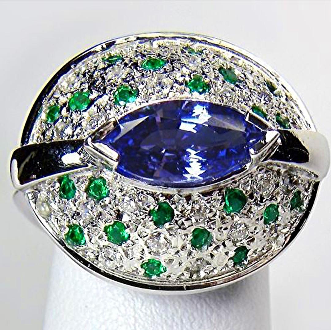 Haz una declaración de intenciones con este impresionante Anillo de Cóctel de Esmeralda y Diamante de Tanzanita natural, Elaborado en oro blanco de 18 quilates, se trata de una creación única y escultural con un elegante racimo de bombas ovaladas