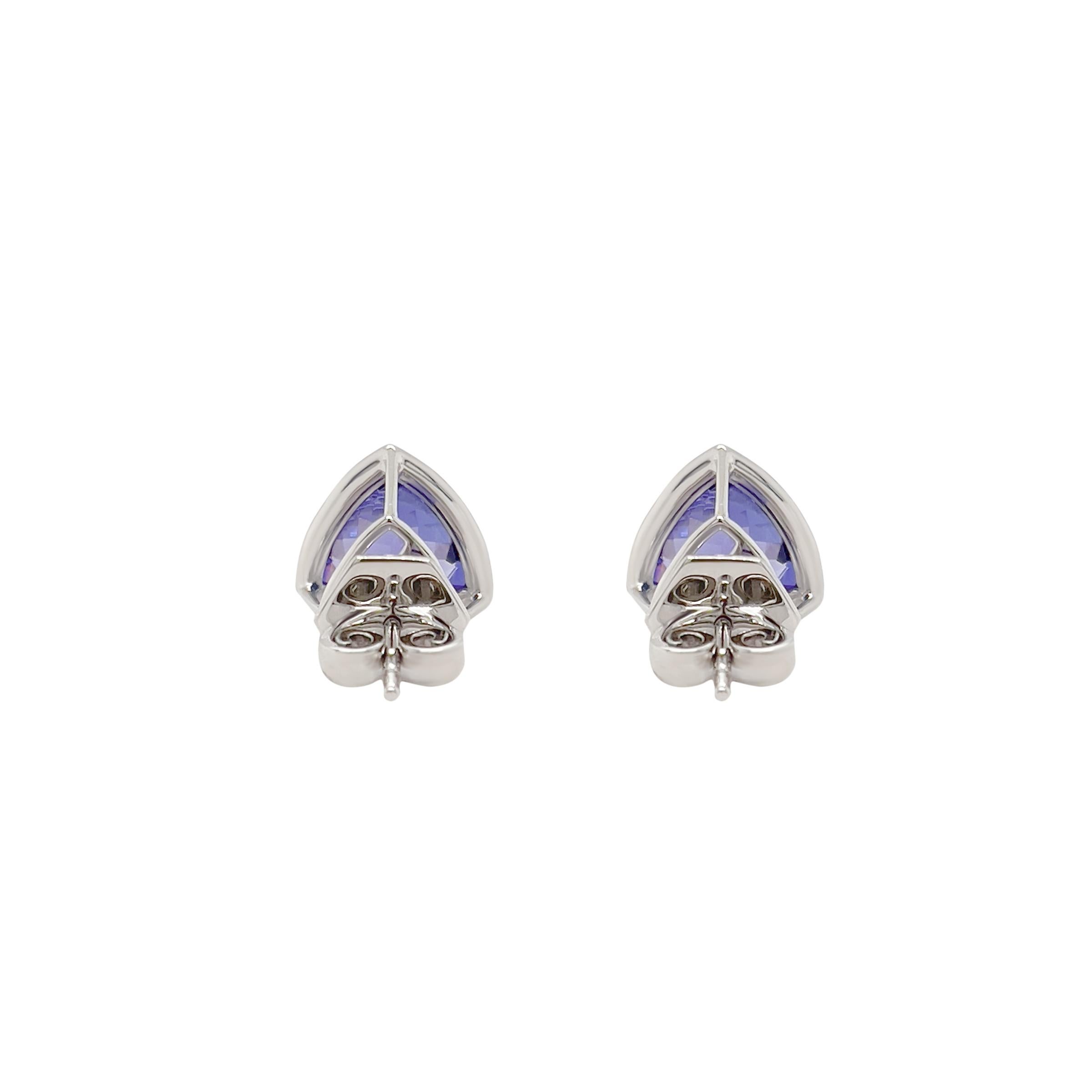 These stunning 3.61ct natural trillion cut tanzanite earrings will be sure to make a statement. The deep velvety blue hue of the tanzanite is contrasted and complemented by the crisp white brilliance of the diamond halo and luxurious 18k white gold