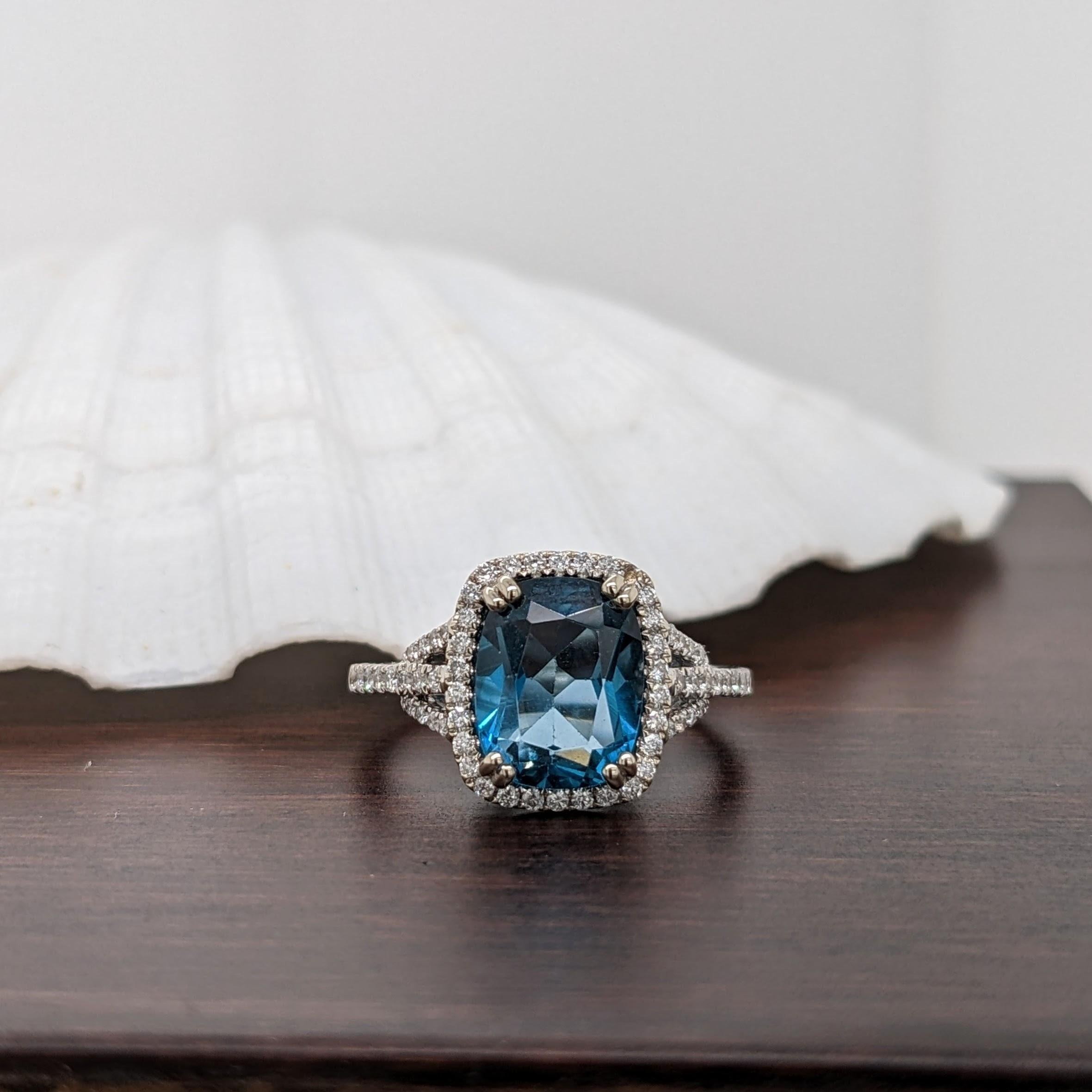 This beautiful ring features a London Blue Topaz in 14k White Gold with a beautiful halo of natural earth-mined Diamond accents. A statement ring design perfect for an eye catching engagement or anniversary. This ring also makes a beautiful December