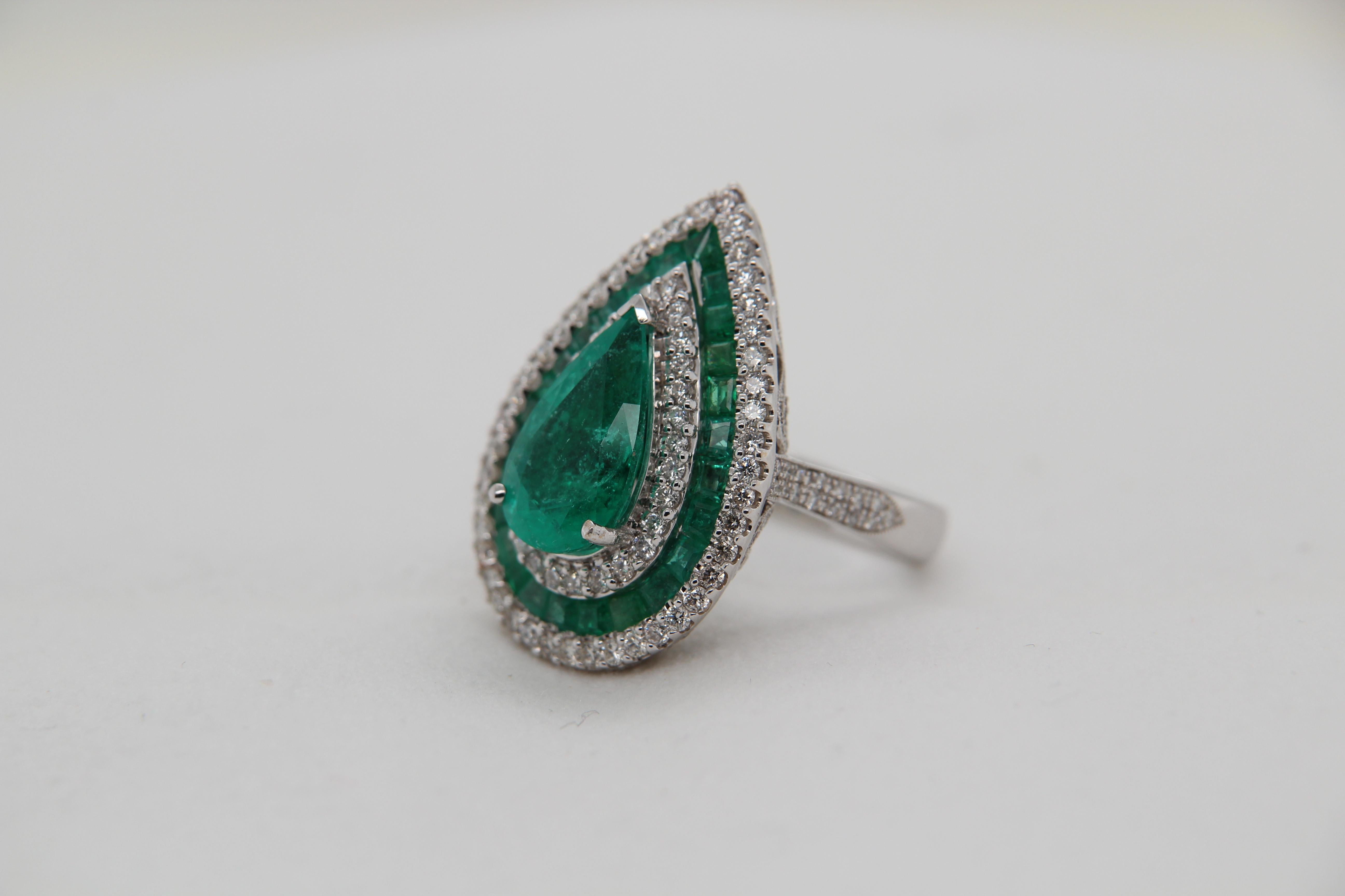A brand new emerald cocktail ring in 18 karat gold. The centre emerald is pear shaped and weighs 3.62 carats and the supporting emeralds weigh 1.30 carats. The diamonds weigh 1.38 carats. The gross weight of the whole ring is 12.01 grams. The ring