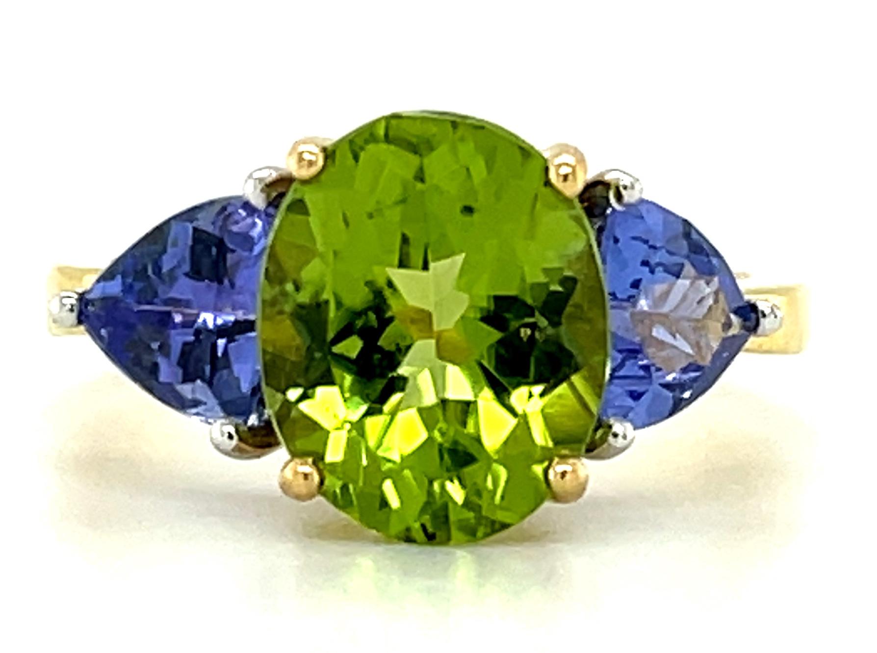 The sophisticated color pairing of green peridot and rich tanzanites in this elegant ring is absolutely mesmerizing! We have combined a gorgeous 3.62 carat brilliant peridot oval with two sparkling trilliant-cut tanzanites in this updated version of