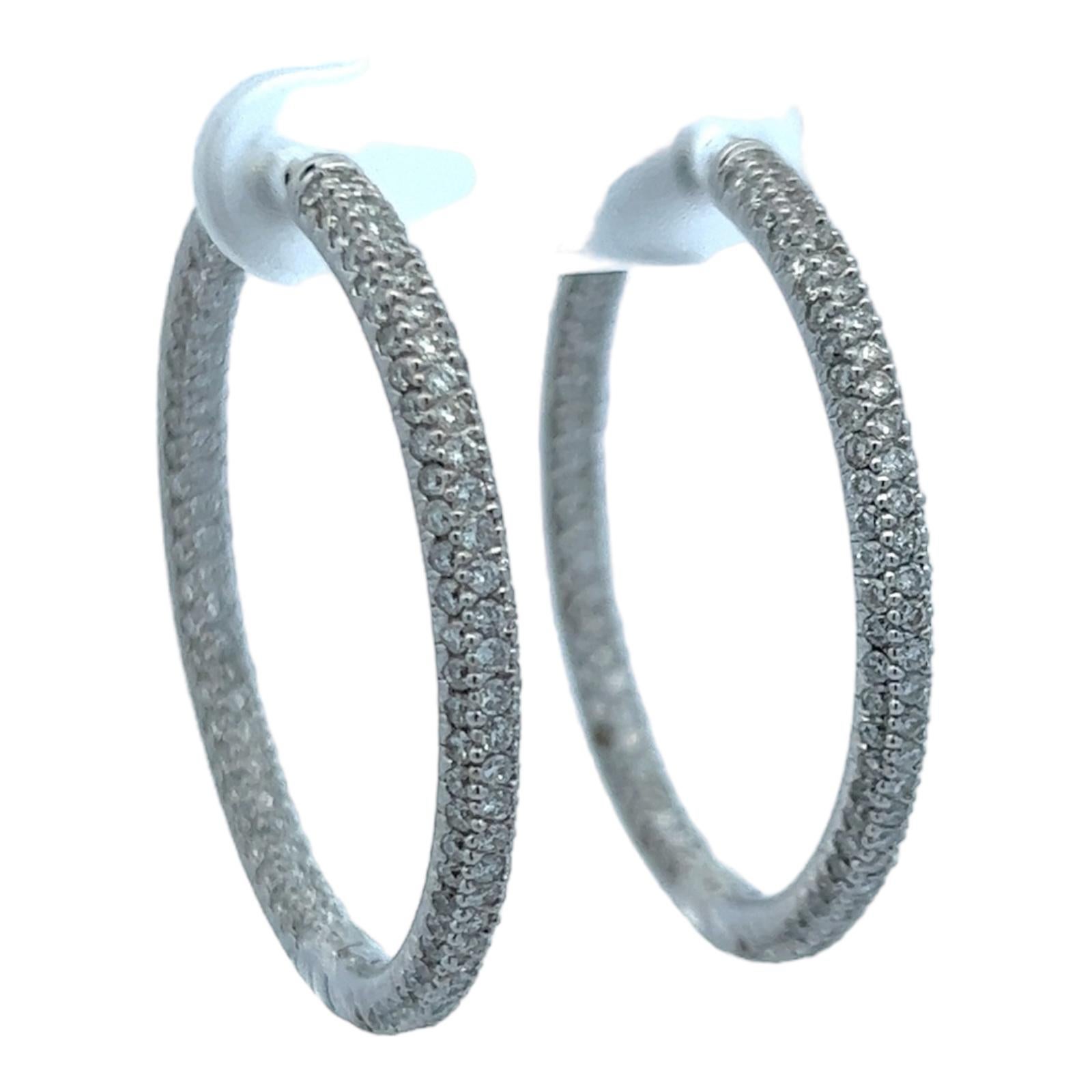 Modern diamond in & out hoop earrings crafted in 18 karat white gold. The hoops feature 3 rows of 362 round briliant cut diamonds weighing approximately 3.62 CTW and Graded H-I color and SI clarity. The 3mm hoops measure 1.25 inches in diameter. 