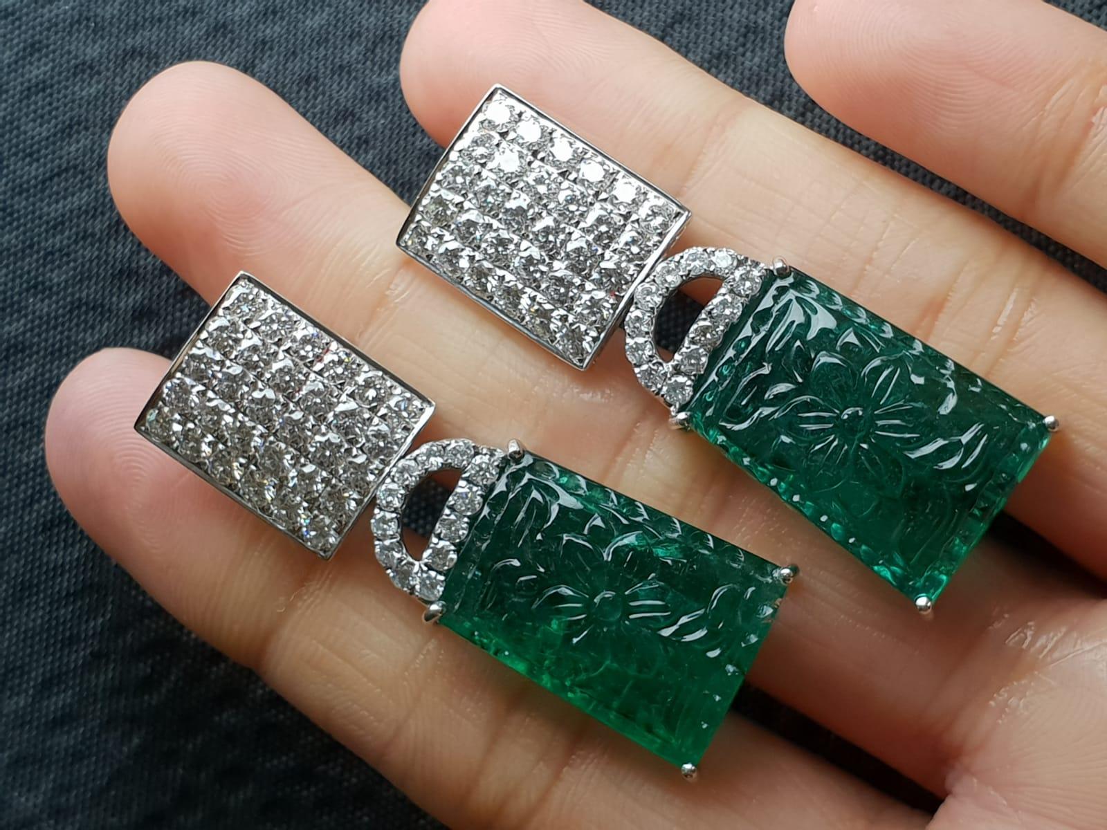 A pair of very unique transparent, top quality carved Zambian Emerald and White Diamond dangling earrings. It comes with an omega backing so this pair can be worn by people who don't have their ears pierced. This earring is made using 18K White